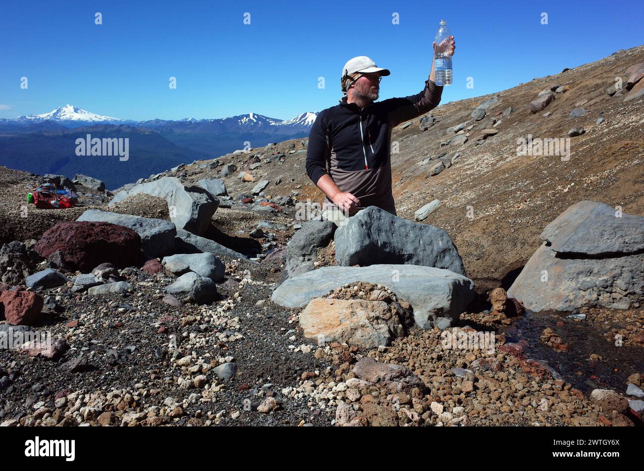 Tourist checking drinking water quality looking plastic bottle, From Mountain stream on mountainside volcano Puyehue in Puyehue National Park, Los Lag Stock Photo
