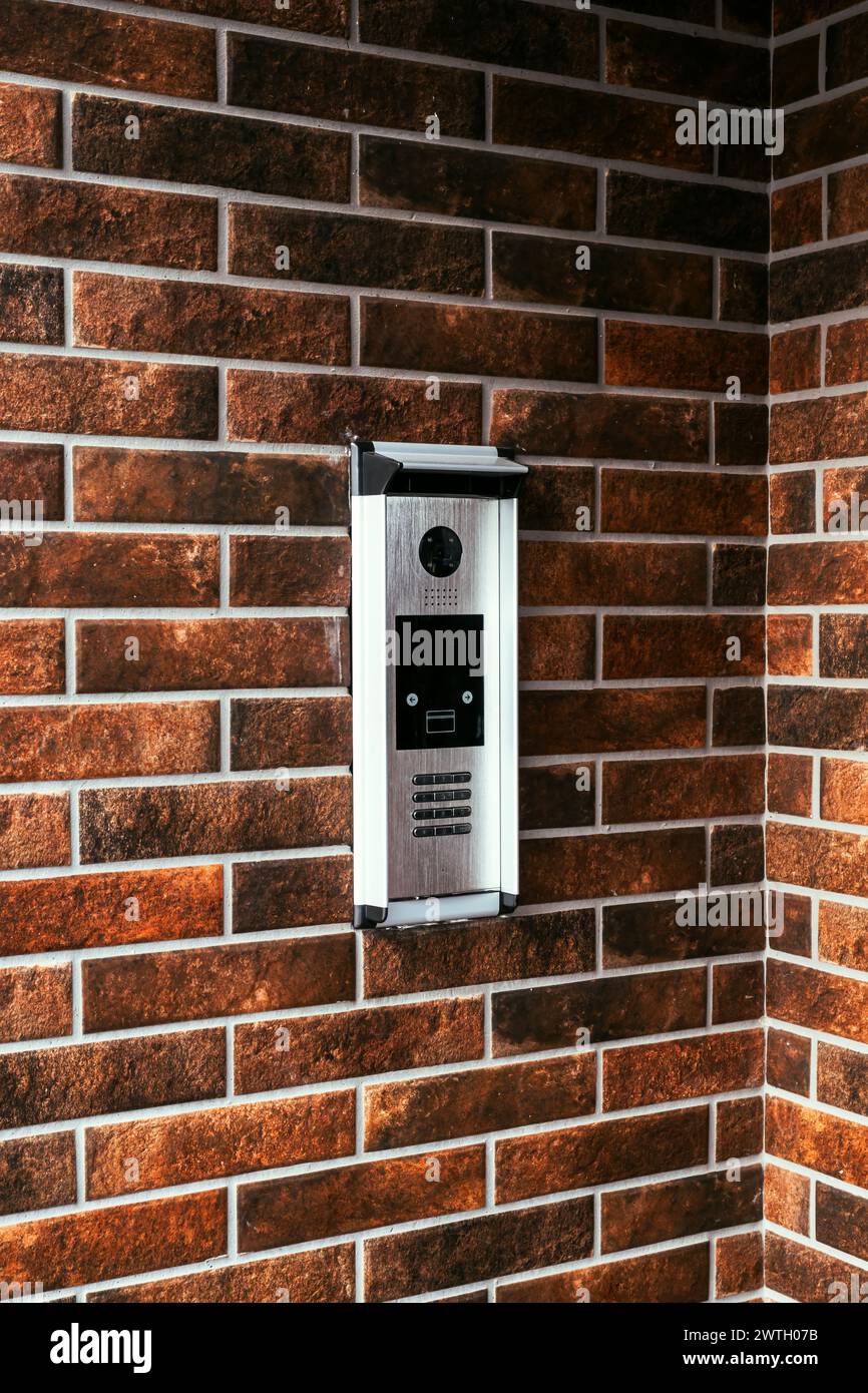 Modern intercom device at residential building entrance door with camera and dial keypad lock, selective focus Stock Photo