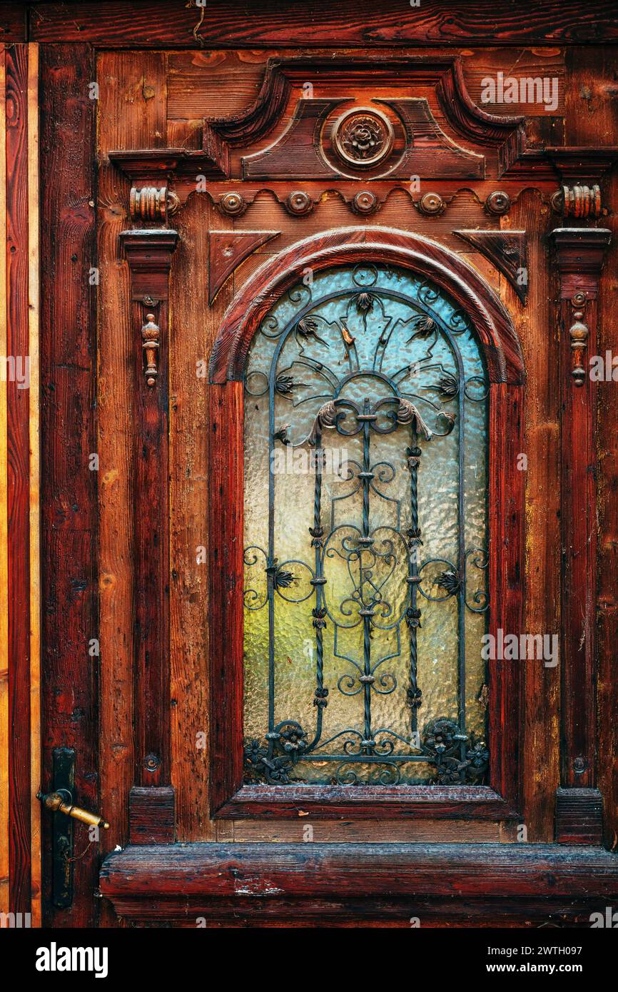 Old vintage wooden door with carving decoration and wrought iron details, selective focus Stock Photo