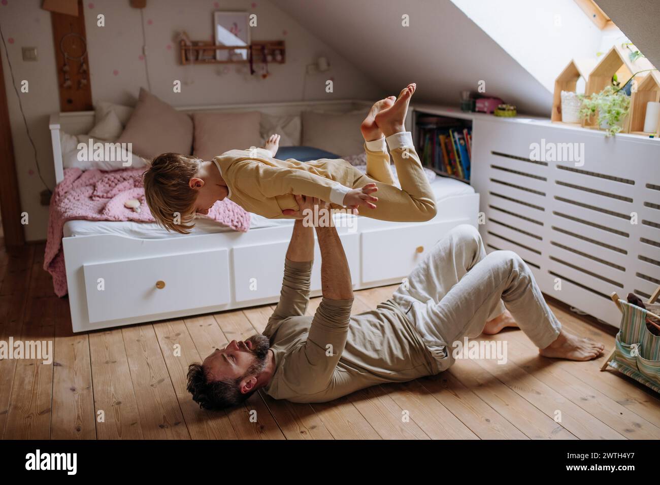 Father an son doing ariplane game, lifting boy up with hands like plane, laughing together. Boys dad. Unconditional paternal love, Father's Day Stock Photo