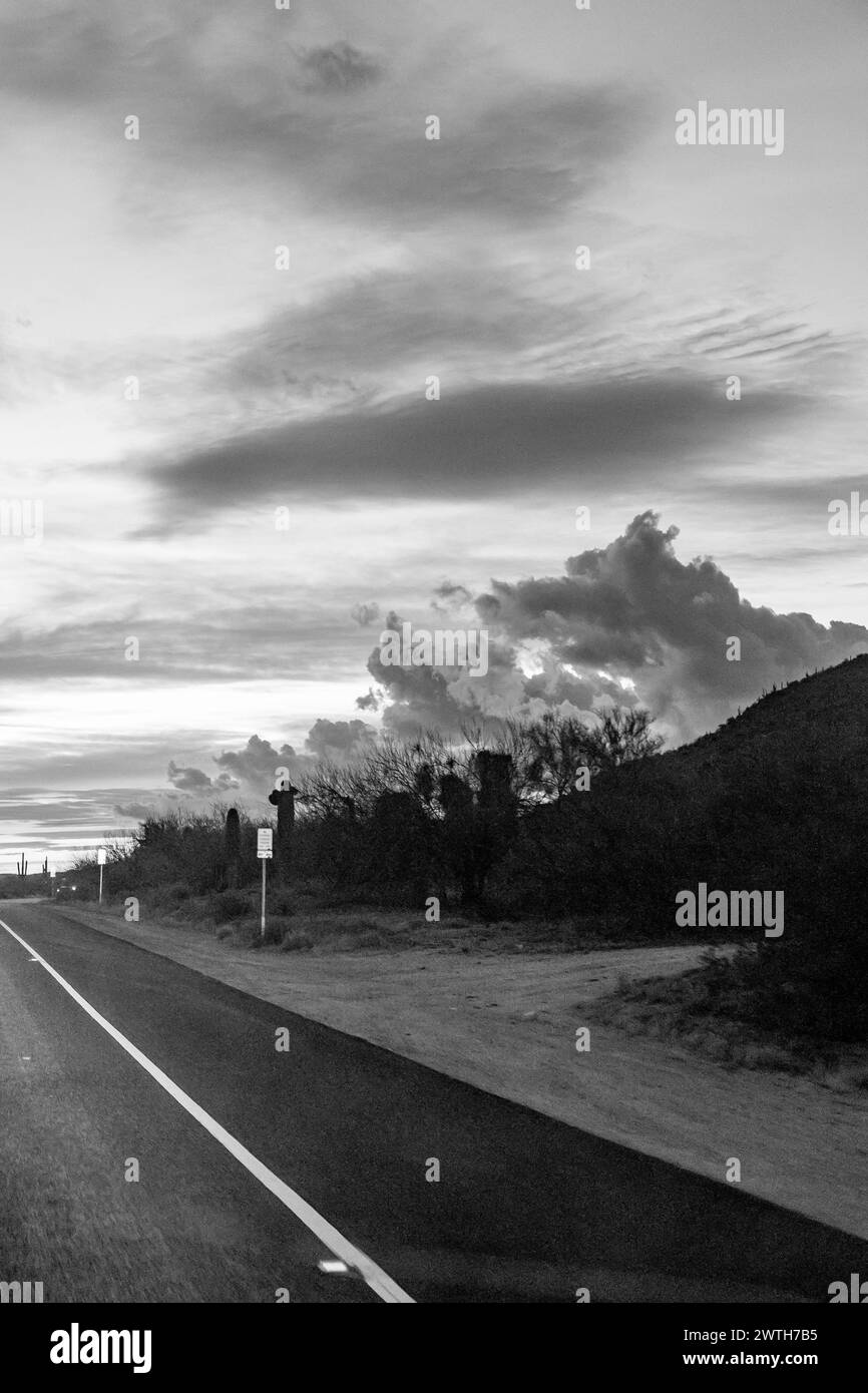 cloudy sky blue puffy clouds sun at sunset dusk black and white Stock Photo