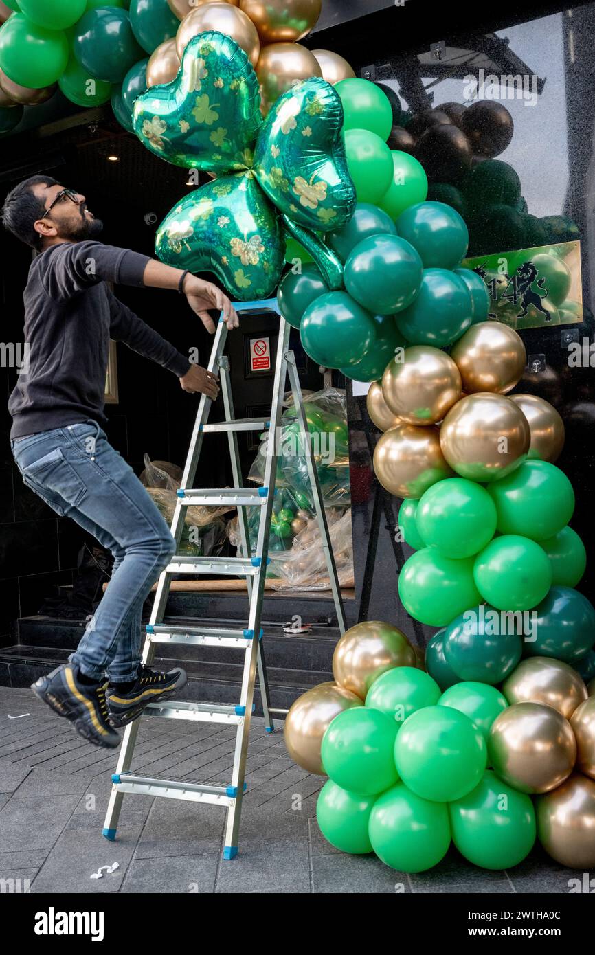 Contractors install St Patrick's Day-themed shamrock-green ballons over the doorway of a West End premises before the Irish weekend celebrations, on 15th March 2024, in London, England. Cousins Sachin and Vivek run 'Festive Floats London', a bespoke party and event balloon business from east London. Stock Photo