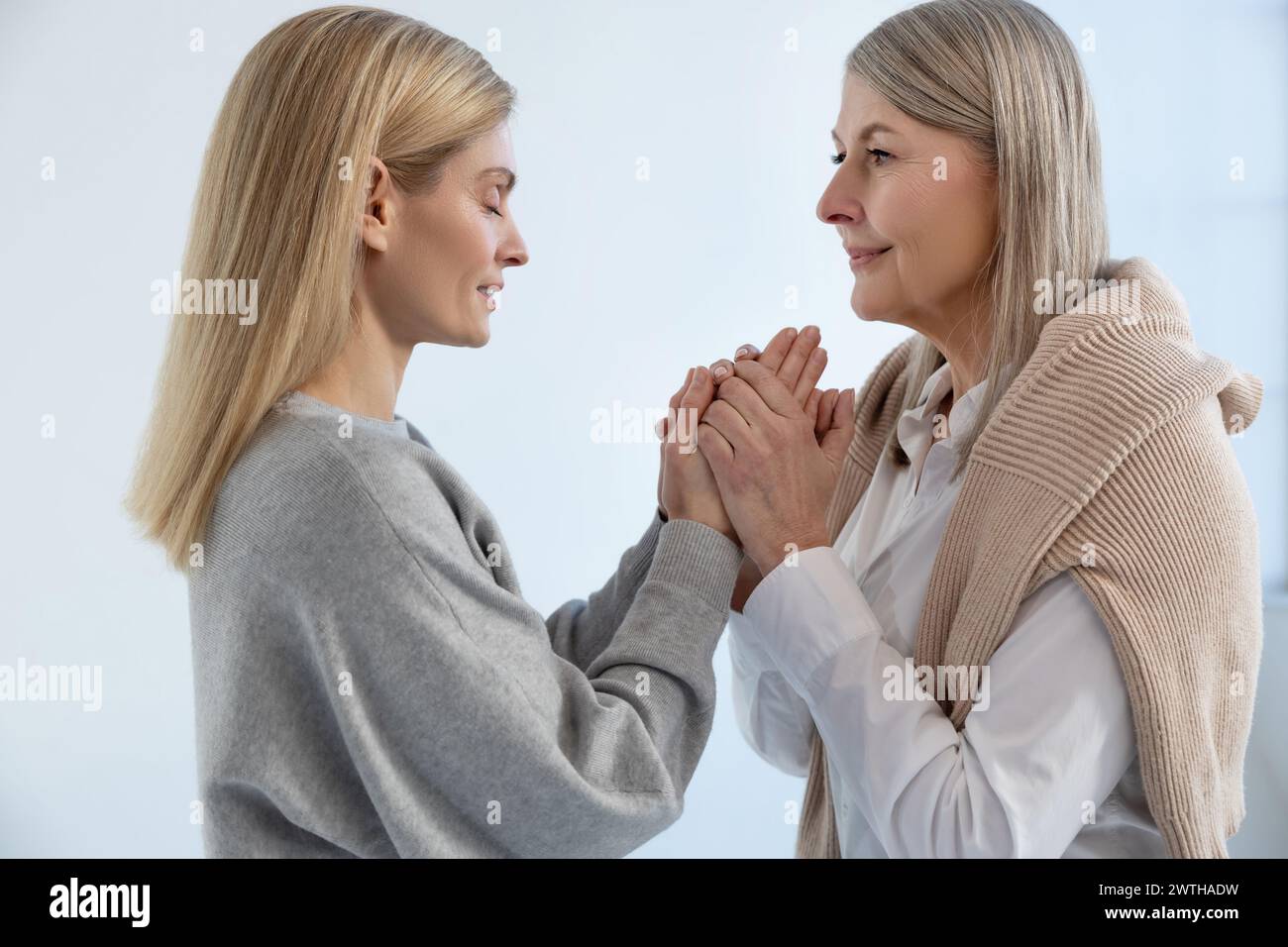 Mother and daughter standing close and holding hands Stock Photo - Alamy