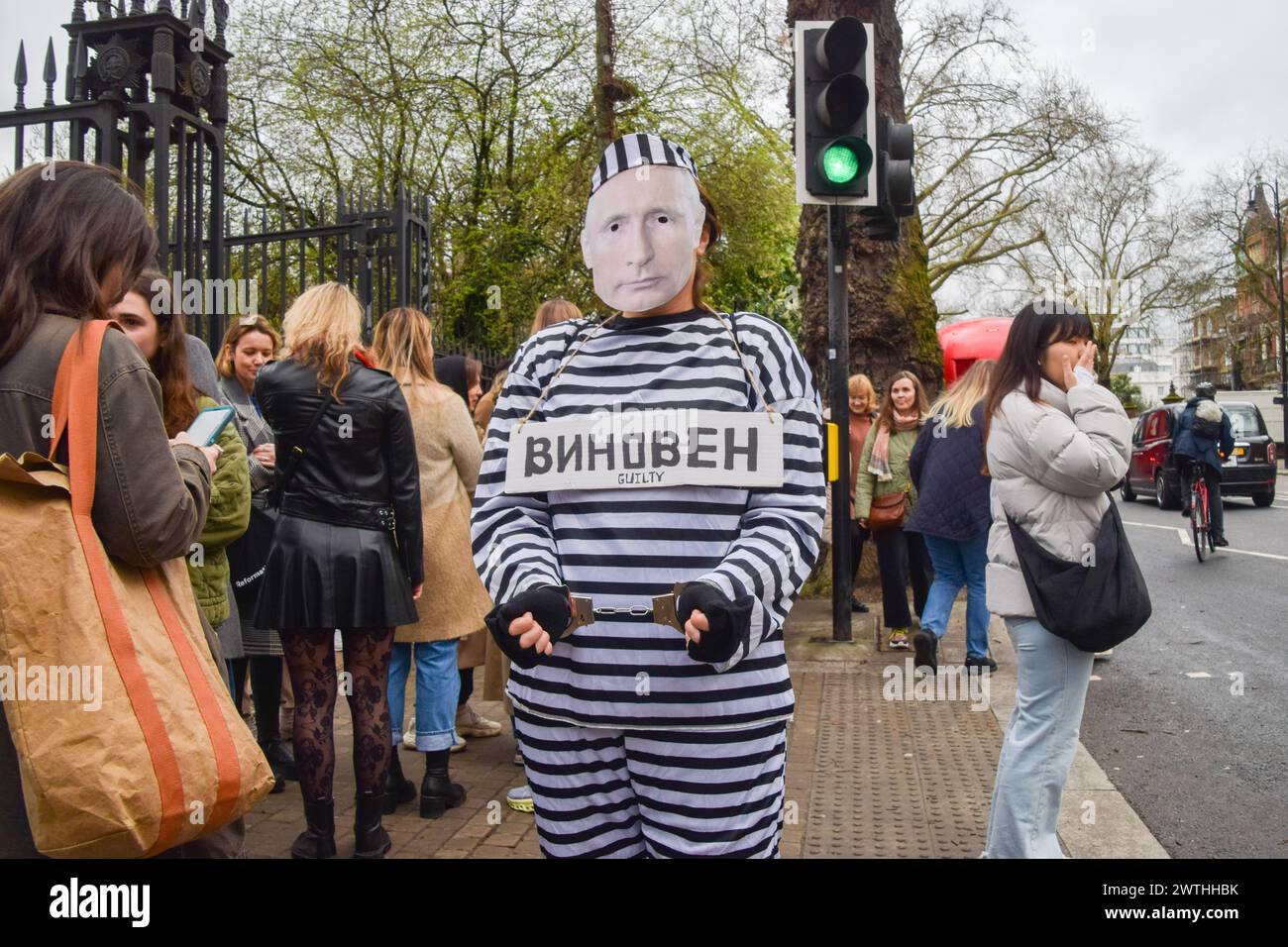 London, UK. 17th March 2024. A protester dressed as Putin in prison clothing and wearing handcuffs walks outside the Russian Embassy past Russian citizens queueing to cast their vote, as elections take place in Russia. Credit: Vuk Valcic/Alamy Live News Stock Photo