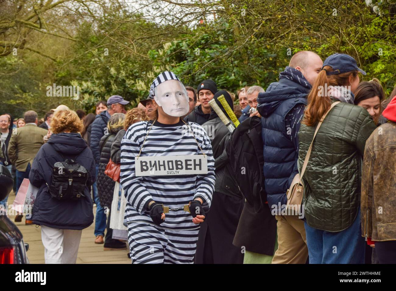 London, UK. 17th March 2024. A protester dressed as Putin in prison clothing and wearing handcuffs walks outside the Russian Embassy past Russian citizens queueing to cast their vote, as elections take place in Russia. Credit: Vuk Valcic/Alamy Live News Stock Photo