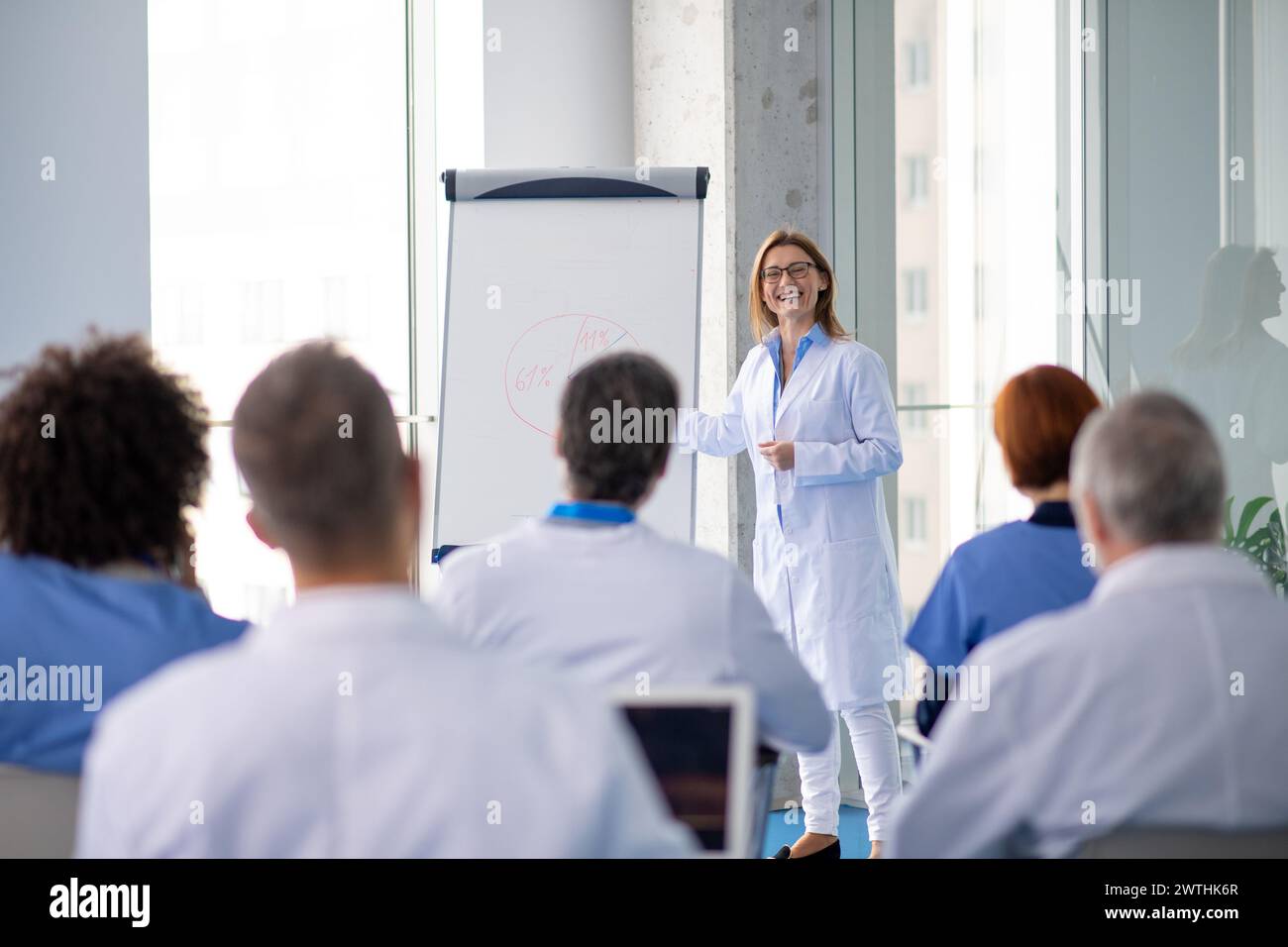 Female doctor as speaker at conference for healtcare workers, medical team sitting and listening presenter. Medical experts attending an education Stock Photo