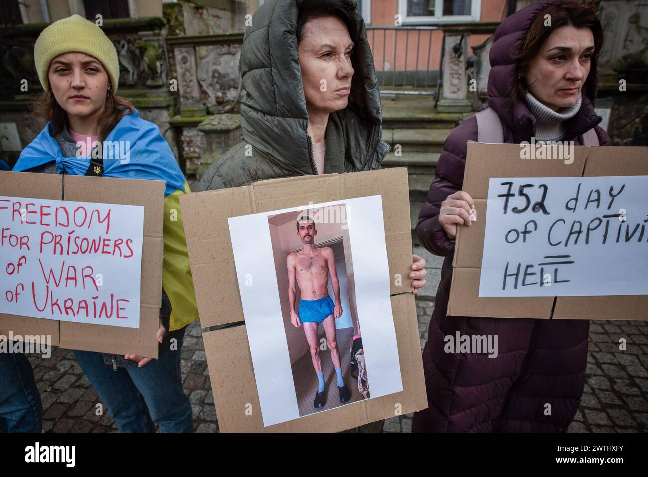 Gdansk, Poland. 16th Mar, 2024. Women hold signs expressing their beliefs during a rally of the Ukrainian community in Gdansk. A rally organized by the Ukrainian community took place in Gdansk. The rally aimed to draw attention to the situation of Ukrainian prisoners of war who are being held in inhumane conditions. They lose their health, are subjected to torture, and often die. During the rally, clothes were laid on the pavement to symbolize the emptiness and longing caused by the separation of families. Credit: SOPA Images Limited/Alamy Live News Stock Photo