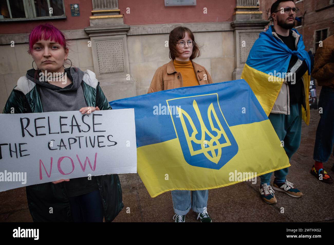 Gdansk, Poland. 16th Mar, 2024. Women hold a placard and flag during a rally of the Ukrainian community in Gdansk. A rally organized by the Ukrainian community took place in Gdansk. The rally aimed to draw attention to the situation of Ukrainian prisoners of war who are being held in inhumane conditions. They lose their health, are subjected to torture, and often die. During the rally, clothes were laid on the pavement to symbolize the emptiness and longing caused by the separation of families. Credit: SOPA Images Limited/Alamy Live News Stock Photo