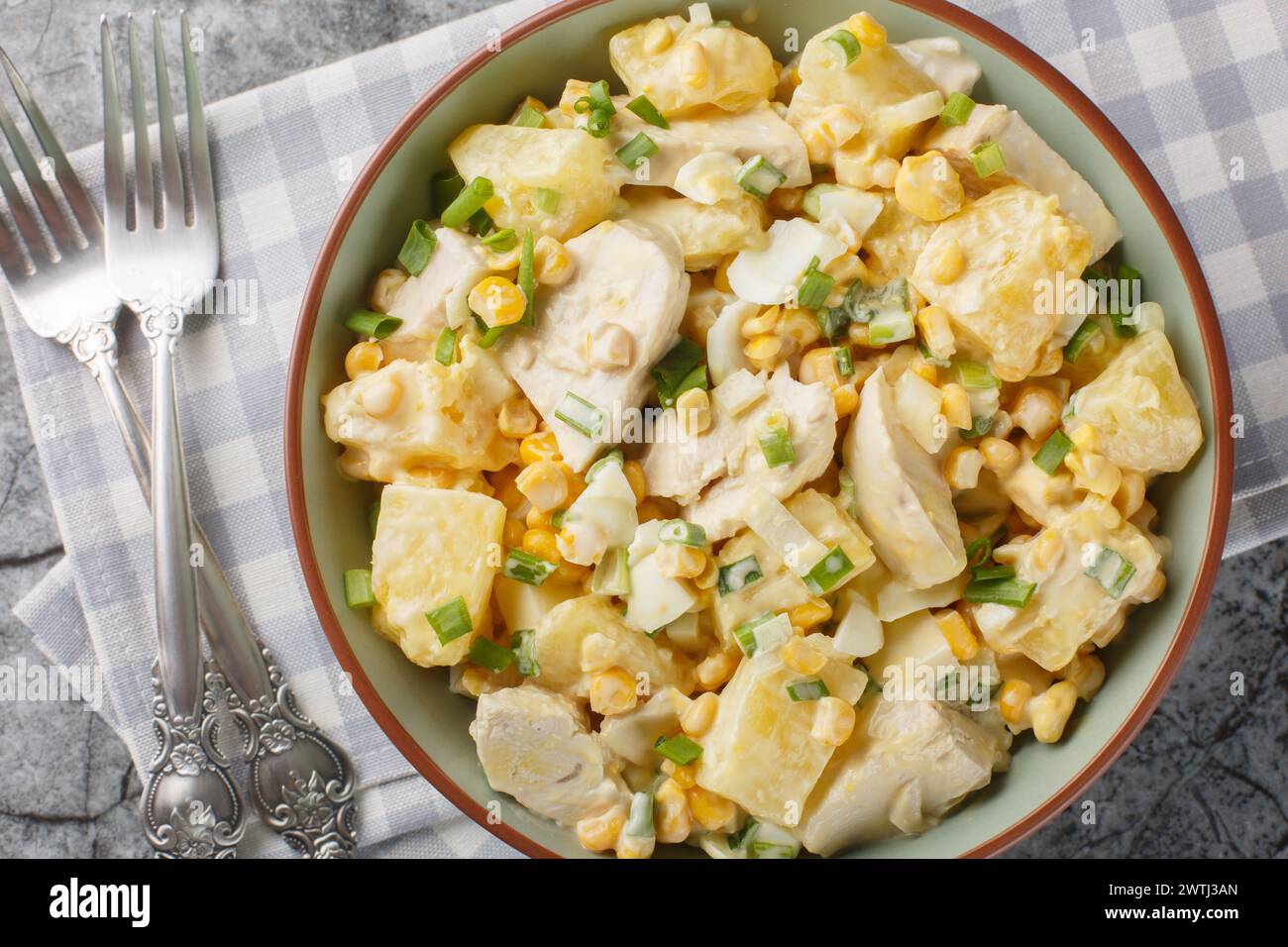 Festive Chicken salad with fresh pineapple, corn, cheese, eggs and onions dressed with mayonnaise close-up in a plate on the table. Horizontal top vie Stock Photo