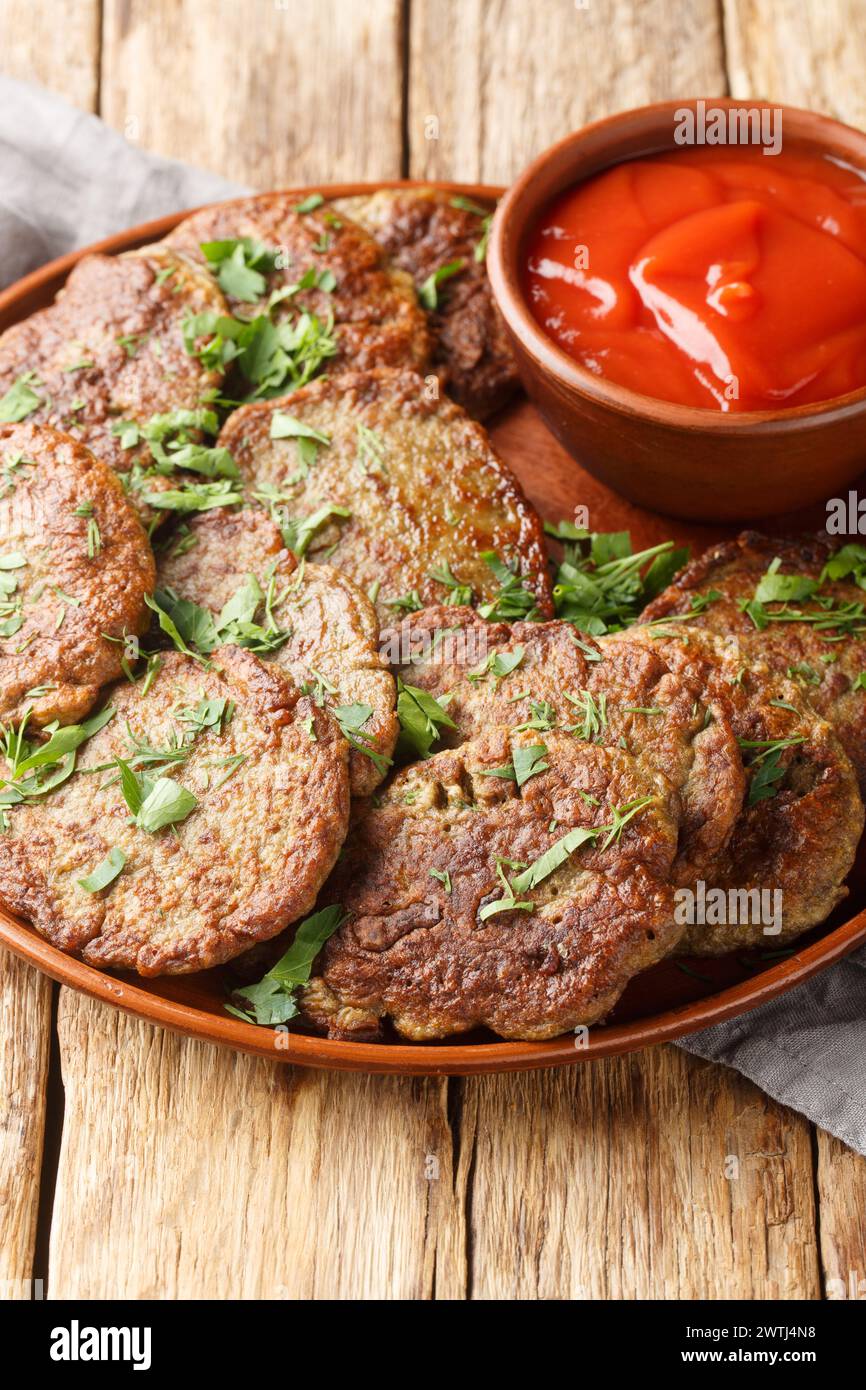 Delicious beef liver patties served with tomato sauce close-up in a plate on the table. Vertical Stock Photo