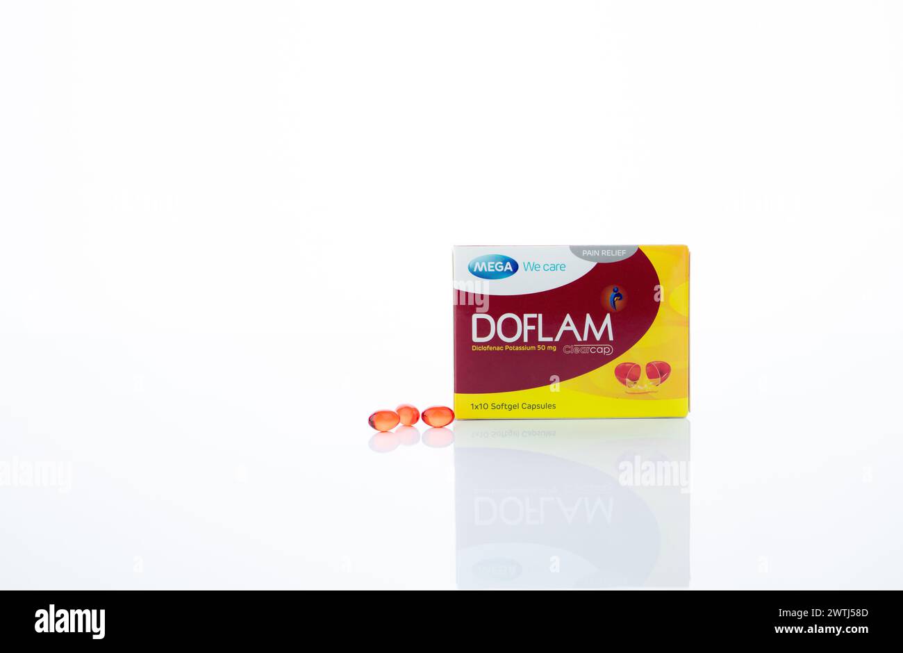 CHONBURI, THAILAND-OCTOBER 08, 2023: Red softgel diclofenac potassium capsules pill and Doflam paper box packaging isolated on white background. Paink Stock Photo