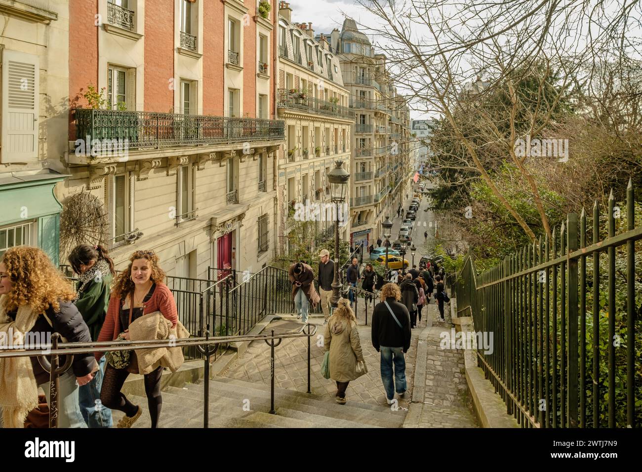 Paris, France - February 17, 2024 : View of tourists walking up and down the picturesque staircases with the lanterns in the Montmartre area in Paris Stock Photo