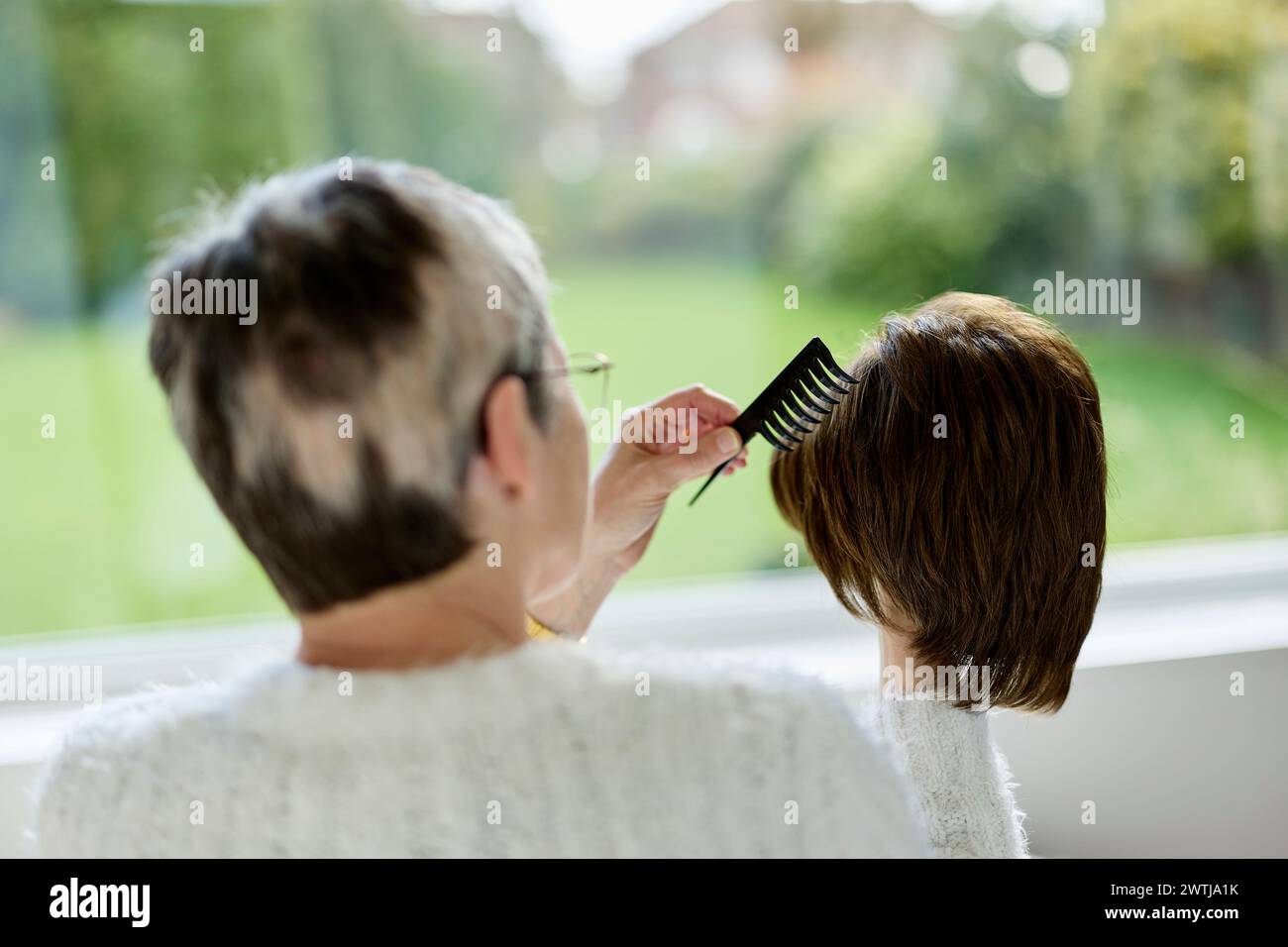 Woman with Alopecia combing a wig Stock Photo