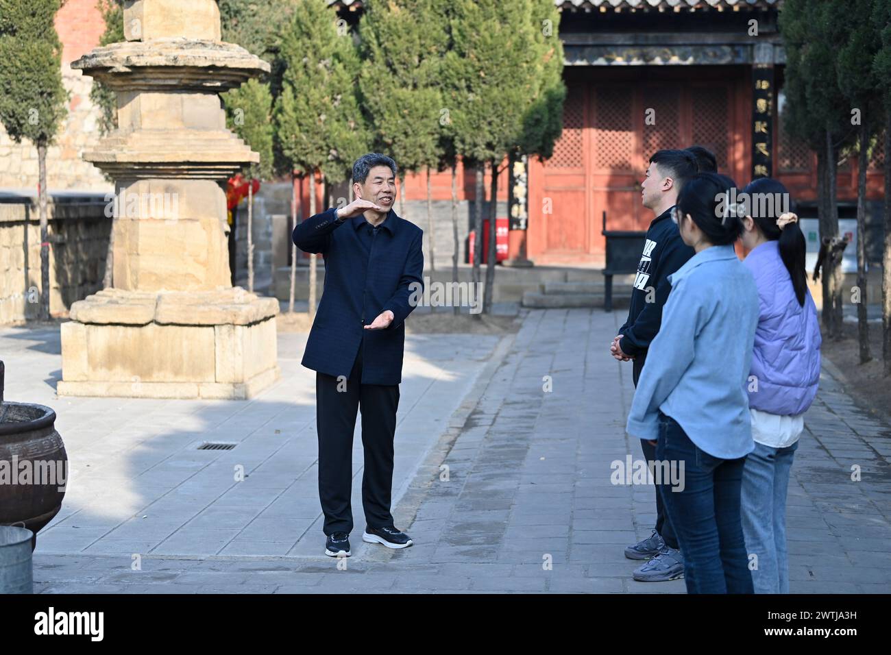 (240318) -- ZHANGZI, March 18, 2024 (Xinhua) -- Zhang Yufei (1st L) guides tourists in Faxing Temple in Zhangzi County, north China's Shanxi Province, March 12, 2024. Faxing Temple, with a history of more than 1,000 years, is nestled on Cuiyun Mountain of Zhangzi County. In 1988, the temple was listed as a national key cultural relics protection site. Zhang Yufei, a cultural relics guardian, has worked at the temple since 1993 when he was 21. Zhang initially took on the temple's daily maintenance. He gradually took an interest in the research of the relics at the temple and began to learn Stock Photo