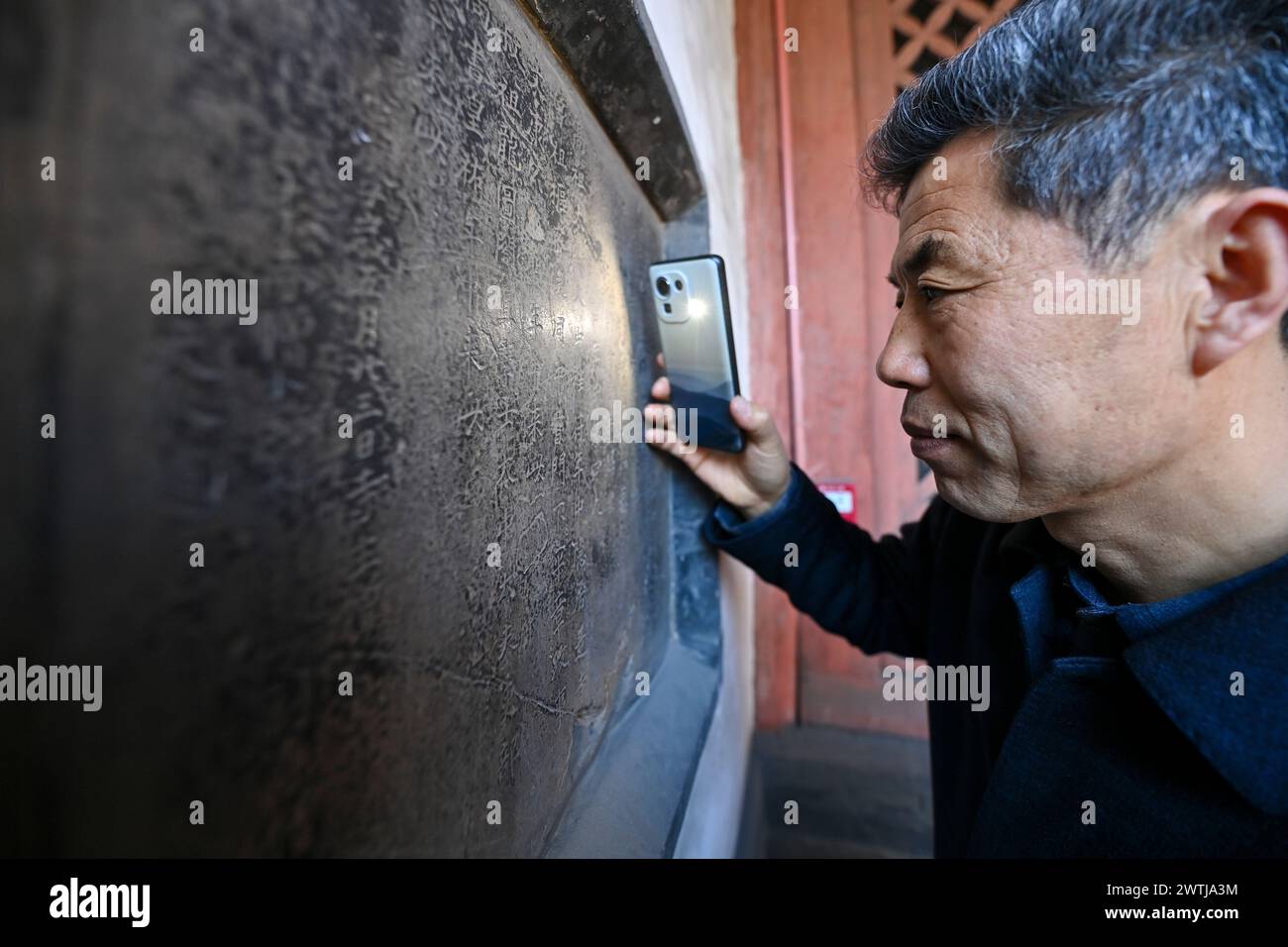 (240318) -- ZHANGZI, March 18, 2024 (Xinhua) -- Zhang Yufei inspects a stone inscription in Faxing Temple in Zhangzi County, north China's Shanxi Province, March 12, 2024. Faxing Temple, with a history of more than 1,000 years, is nestled on Cuiyun Mountain of Zhangzi County. In 1988, the temple was listed as a national key cultural relics protection site. Zhang Yufei, a cultural relics guardian, has worked at the temple since 1993 when he was 21. Zhang initially took on the temple's daily maintenance. He gradually took an interest in the research of the relics at the temple and began to Stock Photo