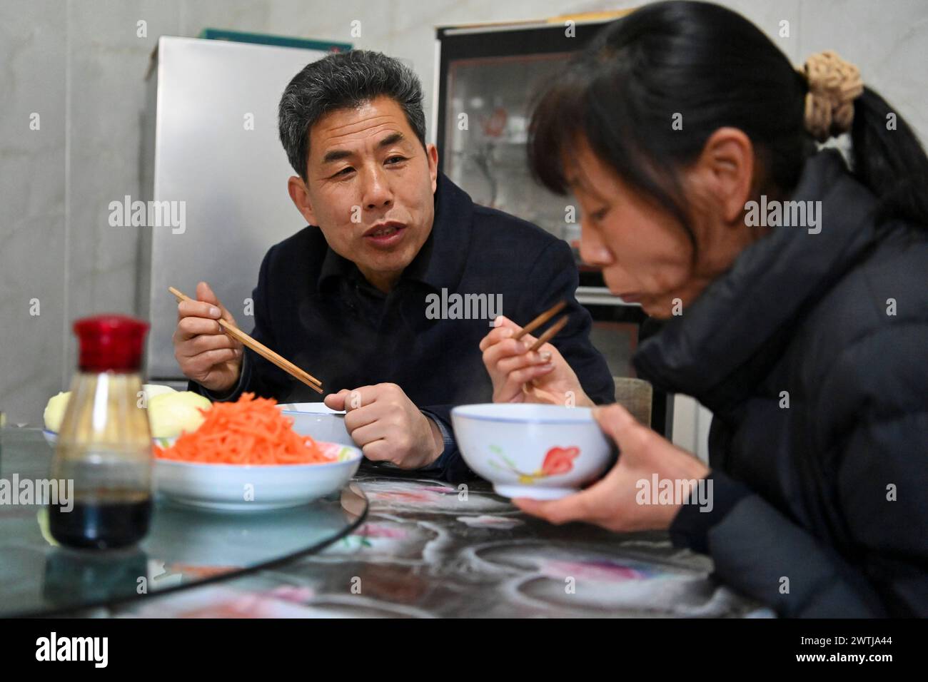 (240318) -- ZHANGZI, March 18, 2024 (Xinhua) -- Zhang Yufei (L) and his wife Liu Hailing have a meal near Faxing Temple in Zhangzi County, north CHina's Shanxi Province, March 12, 2024. Faxing Temple, with a history of more than 1,000 years, is nestled on Cuiyun Mountain of Zhangzi County. In 1988, the temple was listed as a national key cultural relics protection site. Zhang Yufei, a cultural relics guardian, has worked at the temple since 1993 when he was 21. Zhang initially took on the temple's daily maintenance. He gradually took an interest in the research of the relics at the temple Stock Photo