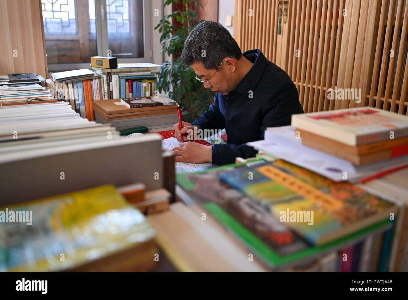 (240318) -- ZHANGZI, March 18, 2024 (Xinhua) -- Zhang Yufei arranges research documents at his home near Faxing Temple in Zhangzi County, north China's Shanxi Province, March 12, 2024. Faxing Temple, with a history of more than 1,000 years, is nestled on Cuiyun Mountain of Zhangzi County. In 1988, the temple was listed as a national key cultural relics protection site. Zhang Yufei, a cultural relics guardian, has worked at the temple since 1993 when he was 21. Zhang initially took on the temple's daily maintenance. He gradually took an interest in the research of the relics at the temple Stock Photo
