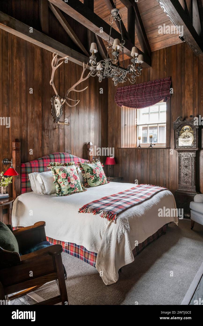 Wall mounted antlers above bed with tartan blanket in luxury hotel in Ardfin on the Isle of Jura, Inner Hebrides, Scotland, UK Stock Photo
