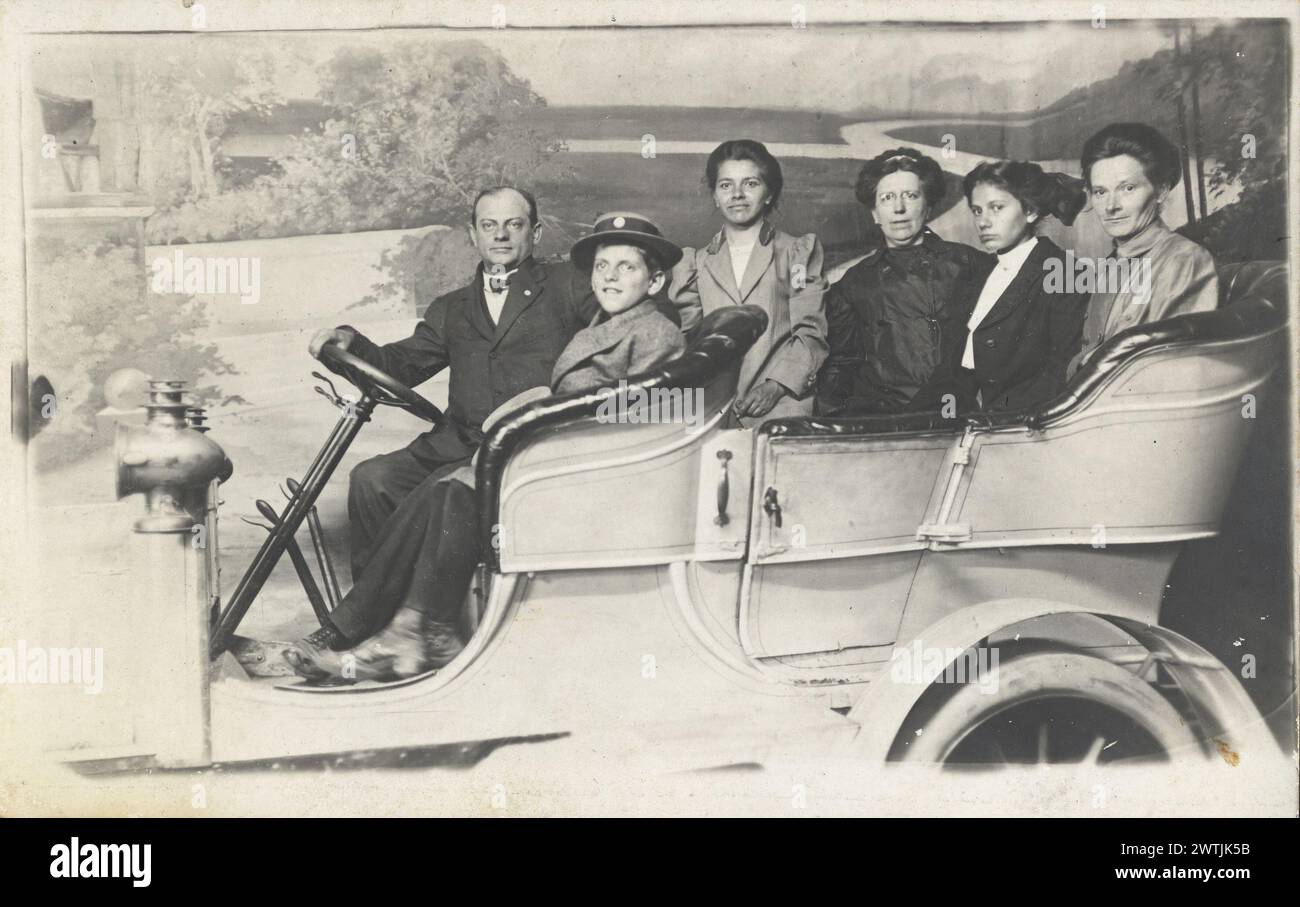 Six people posing in car at a fairground photo booth with painted backdrop.  Riverview Exposition Chicago, taken by Foster & Coultry Official Photographers. Circa 1910. Vintage womens fashions Stock Photo