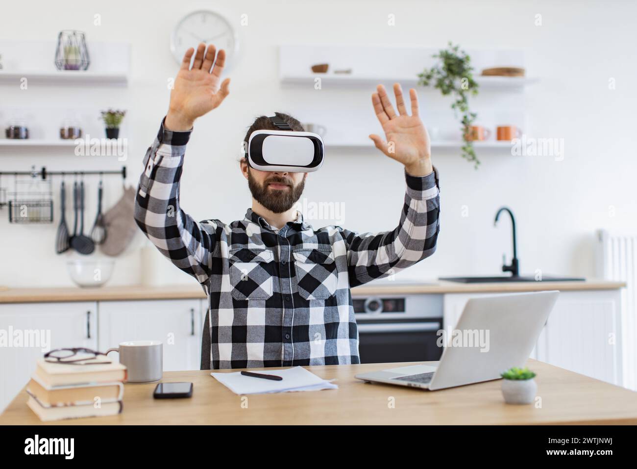 Caucasian worker testing VR headset while sitting at wooden table. Stock Photo