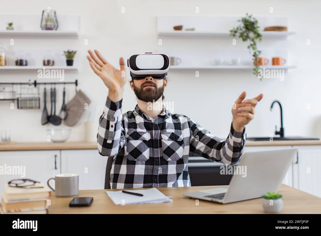 Caucasian worker testing VR headset while sitting at wooden table. Stock Photo