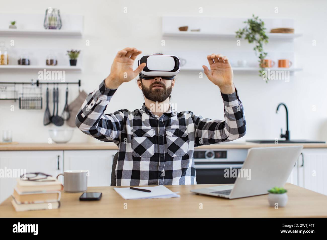 Caucasian worker testing VR headset while sitting at wooden table. Stock Photo