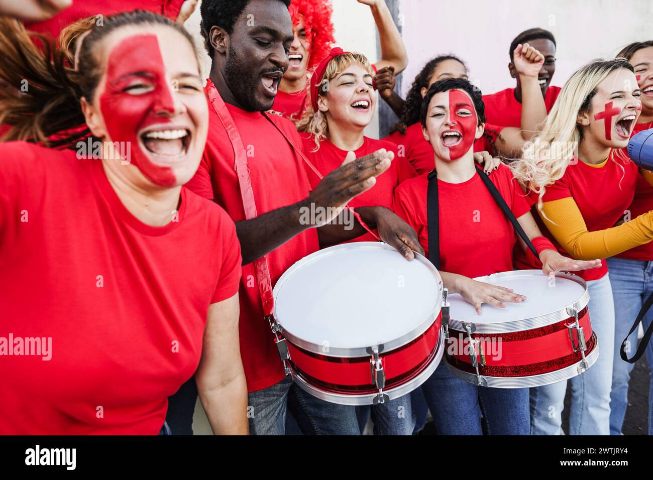 Multiracial sport fans singing while supporting their team - Football supporters having fun outside of stadium wearing red t-shirts - Event and bettin Stock Photo