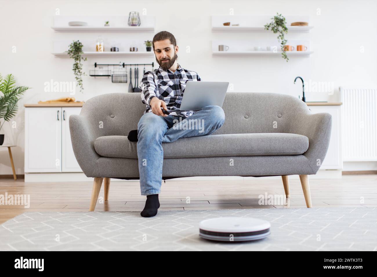 Robotic vacuum removing dust from carpet while Caucasian homeowner