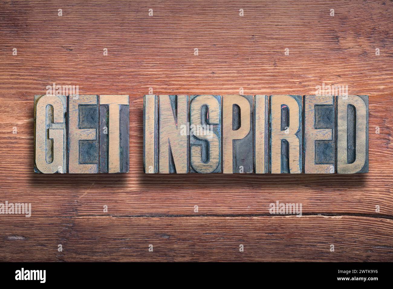 get inspired phrase combined on vintage varnished wooden surface Stock Photo