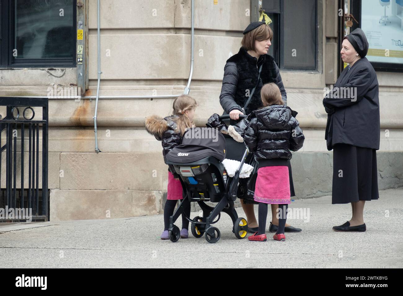 A street scene with 2 hasidic Jewish women, one with kids, talking to one another. In Brooklyn, New York. Stock Photo