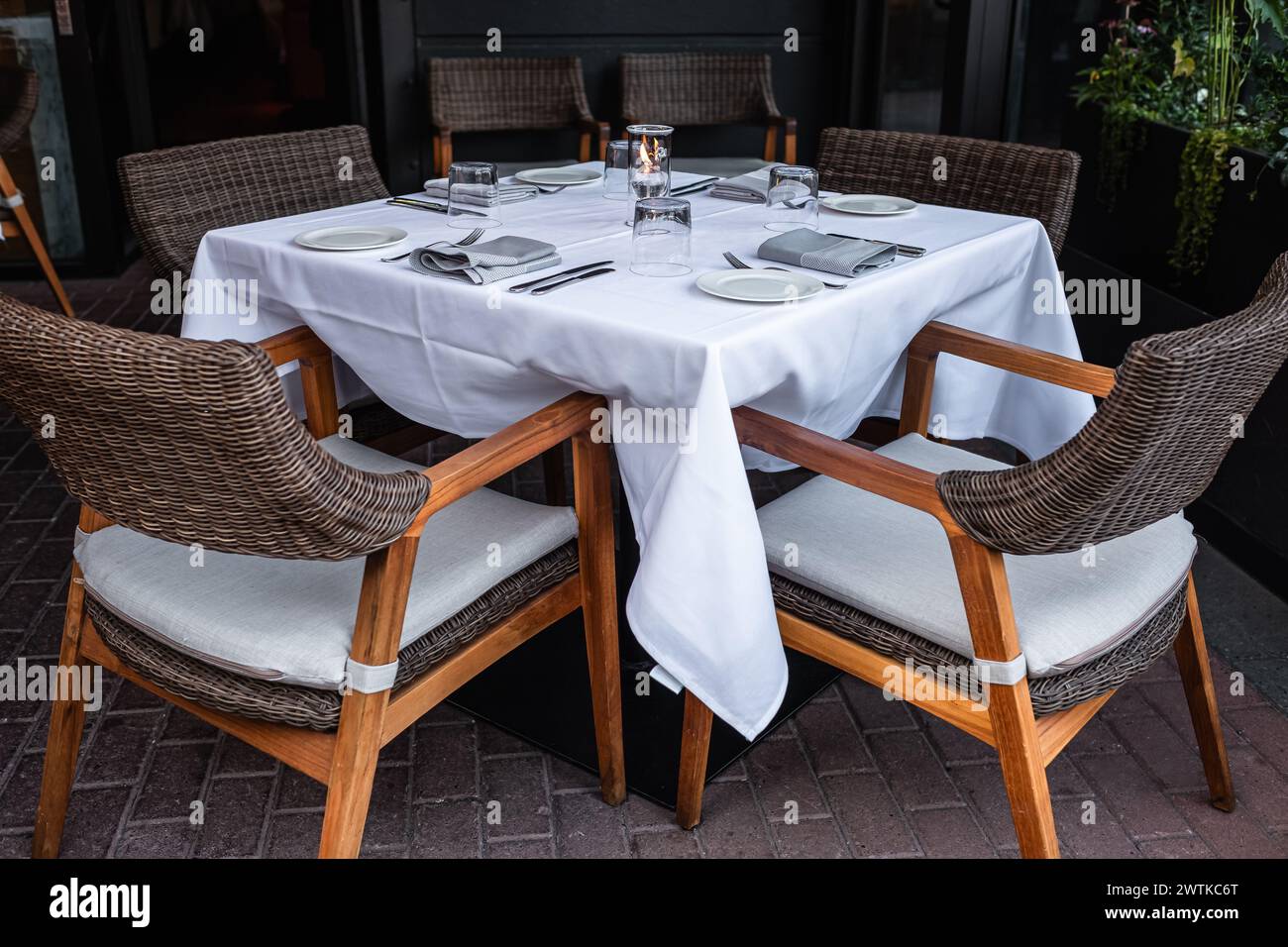 Drinking glasses and table setting on table. Interior of a summer terrace of restaurant. Table and chairs in empty cafe. Outdoor empty coffee and rest Stock Photo