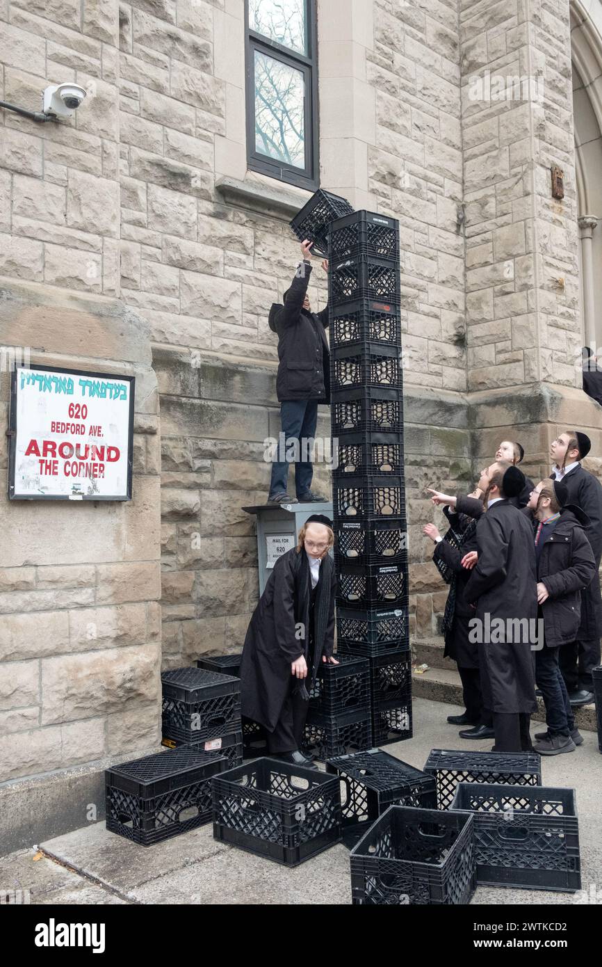 Ultra orthodox Jewish yeshiva students at an urban school build a tower out of milk crates during their recess. In New York City. Stock Photo