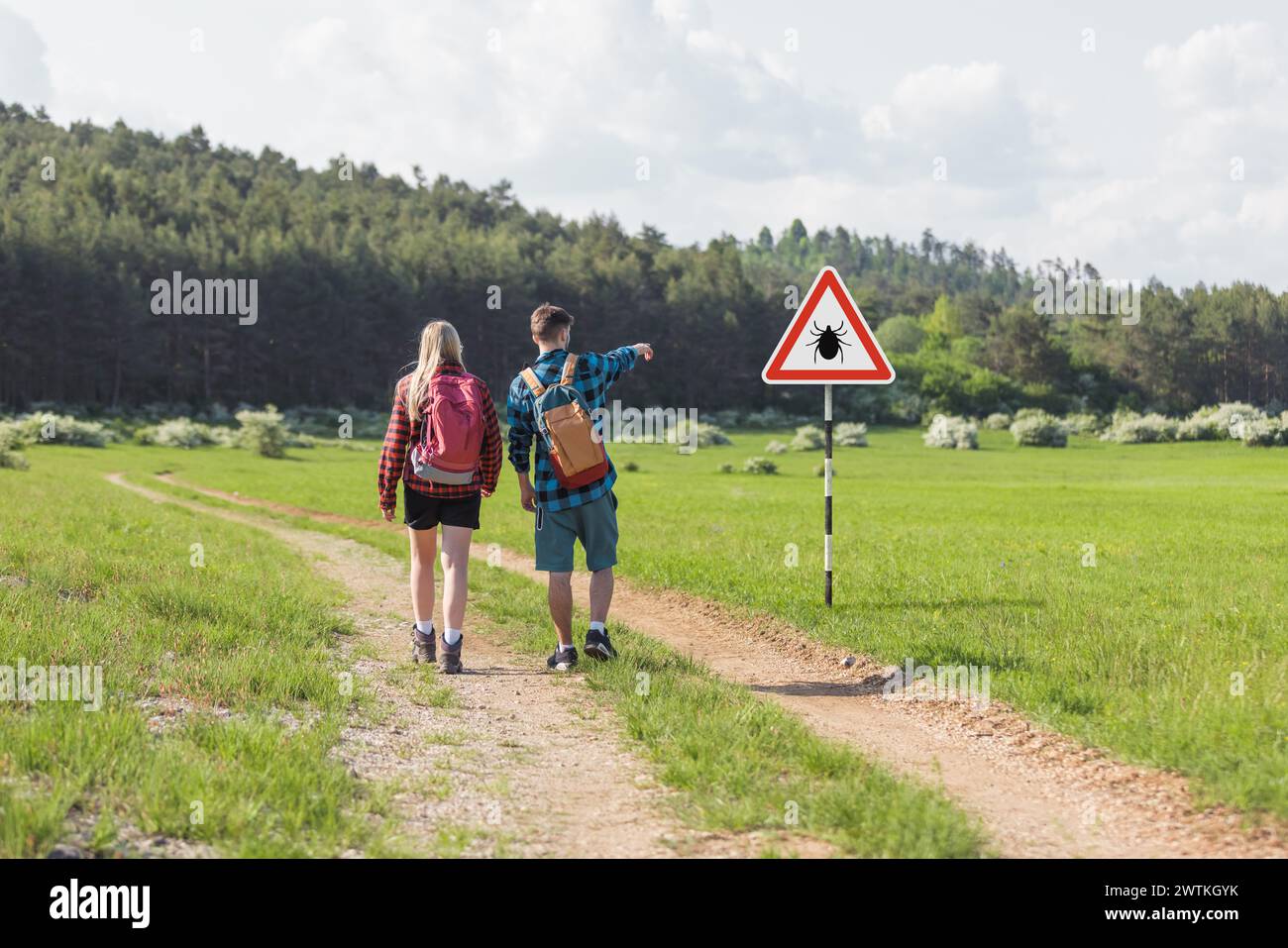 Hikers walking past tick Infected area with danger sign. Risk of tick