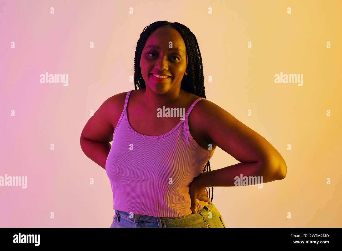 Portrait of smiling Black woman with braided hair standing in neon ...