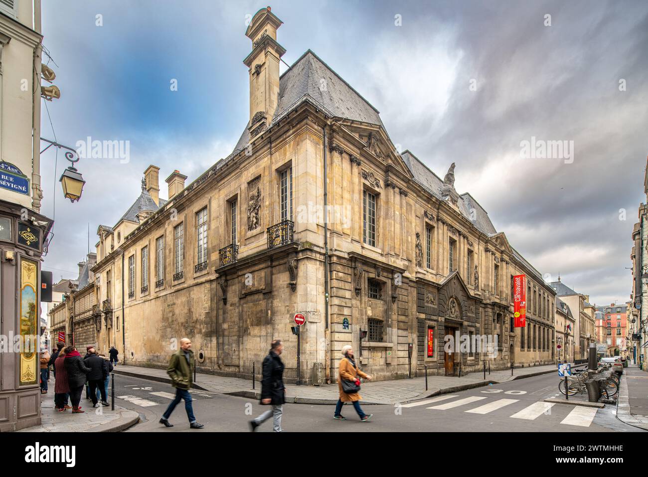 Group of pedestrians crossing a street in front of Carnavalet Museum, a historic building in Paris. Stock Photo