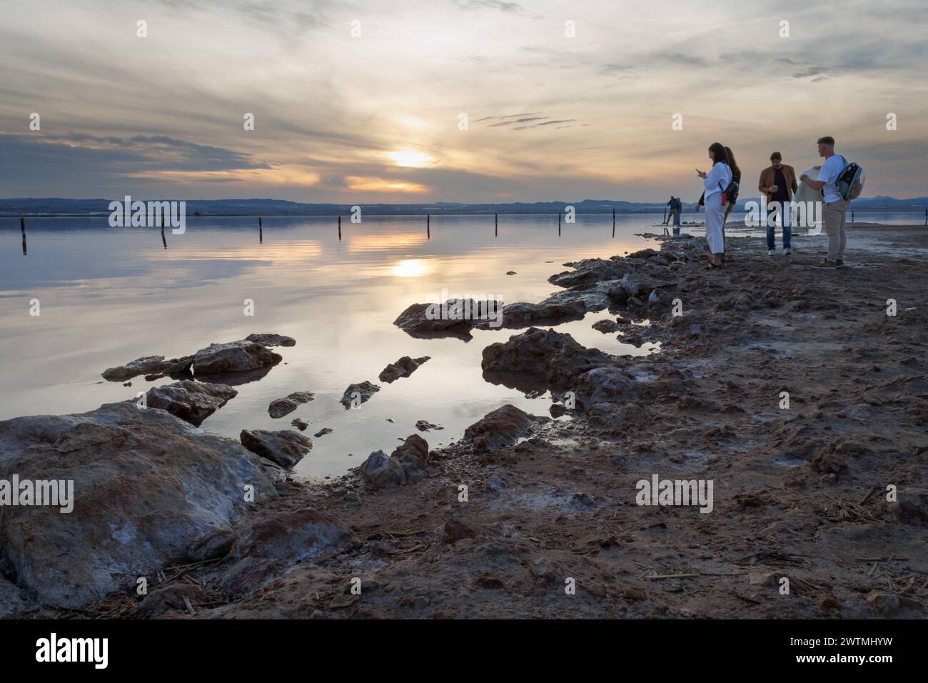Torrevieja, Spain, 03/16/2024: Landscape with people watching the sunset in the pink lagoon of Torrevieja. Spain Stock Photo