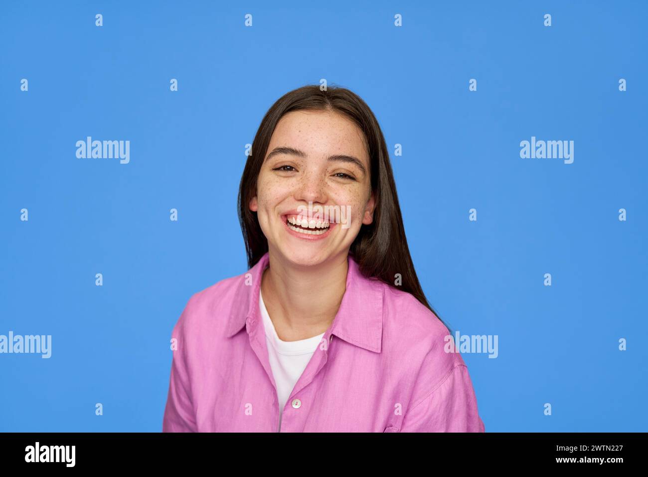 Smiling Latin teen girl student looking at camera isolated on blue background. Stock Photo