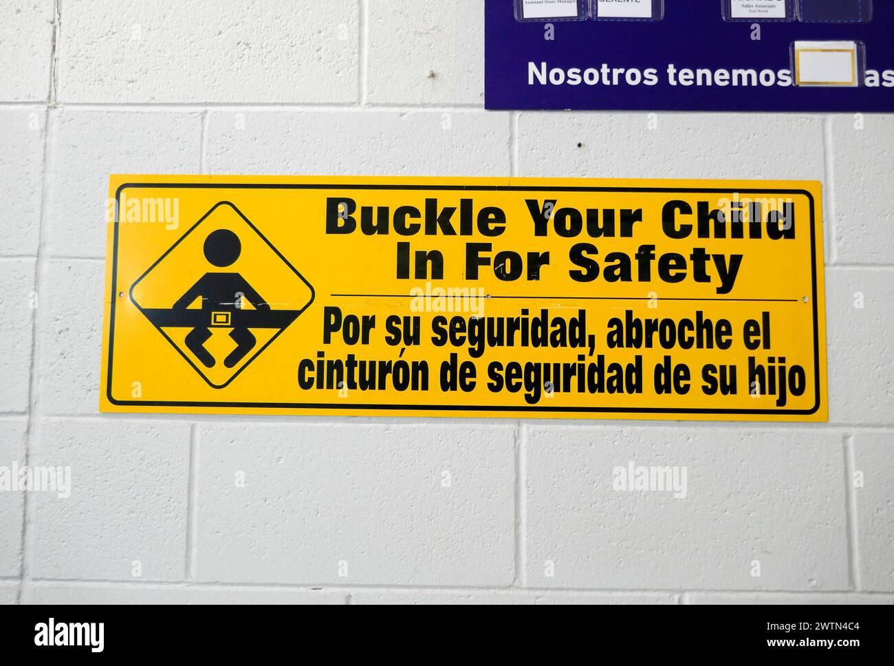 Sign warning parents to safely secure their children in a shopping cart. English and Spanish. Stock Photo