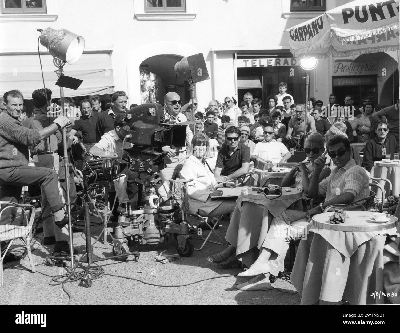 A candid photo of British Actress JULIE CHRISTIE and ROLAND CURRAM with JOHN SCHLESINGER and the camera crew filming a scene in Capri for DARLING 1965  Director JOHN SCHLESINGER  Screenplay FREDERIC RAPHAEL Costume Design JULIE HARRIS Music JOHN DANKWORTH Vic-Appia Films / Anglo Amalgamated Stock Photo