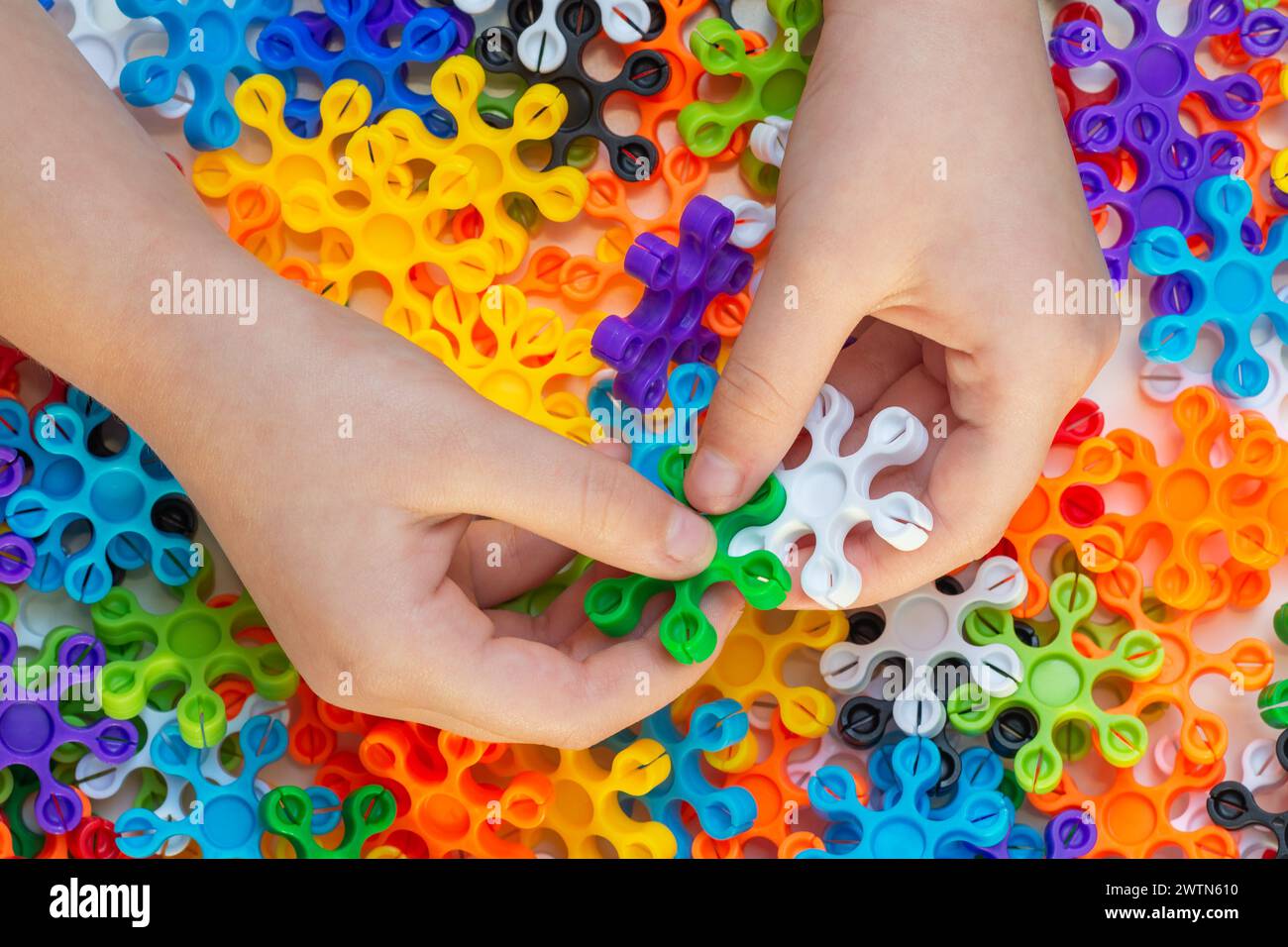 Kid hands playing with colorful connector toy. Educational activity concept with building blocks Stock Photo