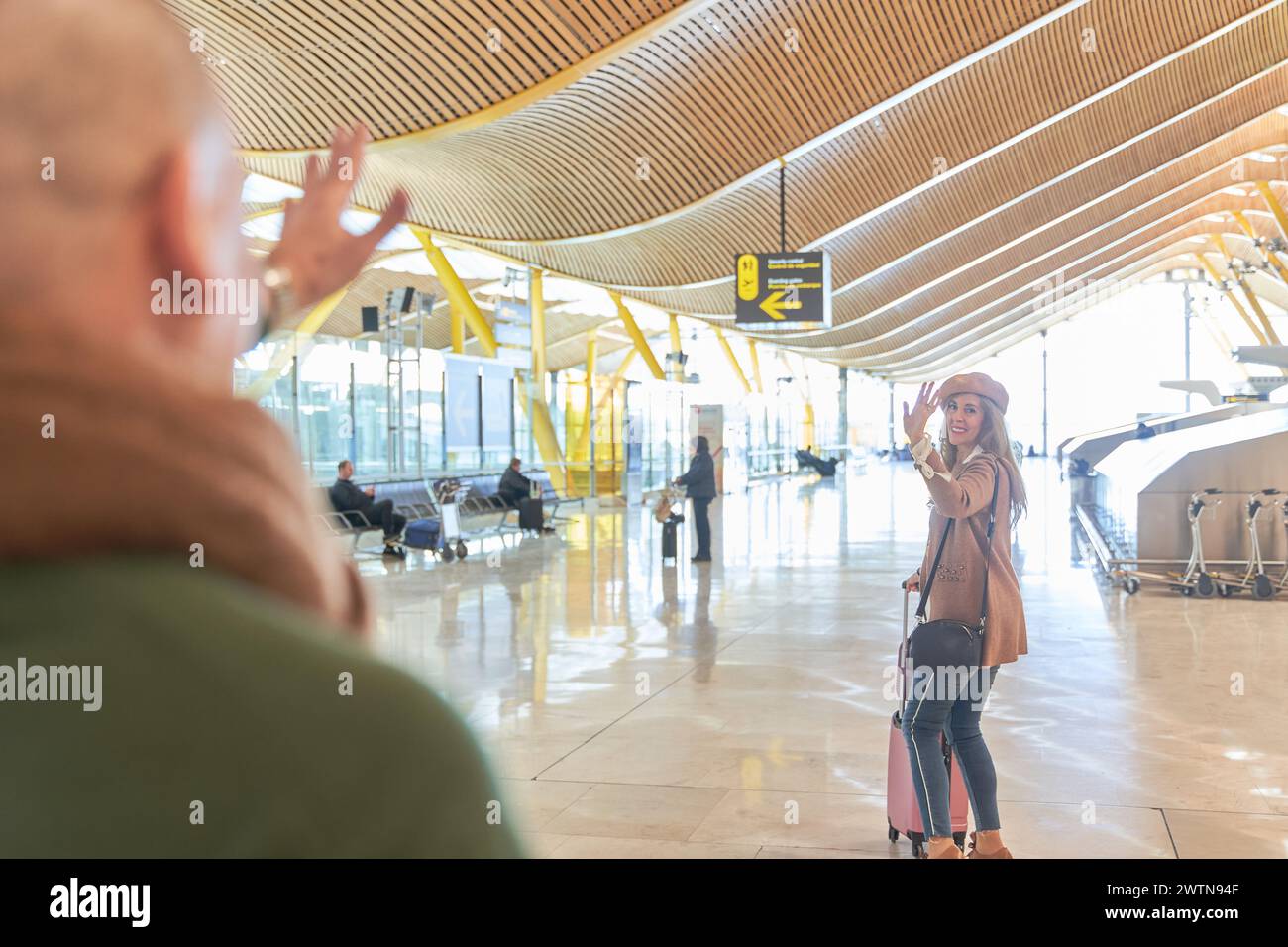 couple in love saying goodbye. woman raises her arm in farewell to her partner at the airport terminal. Stock Photo