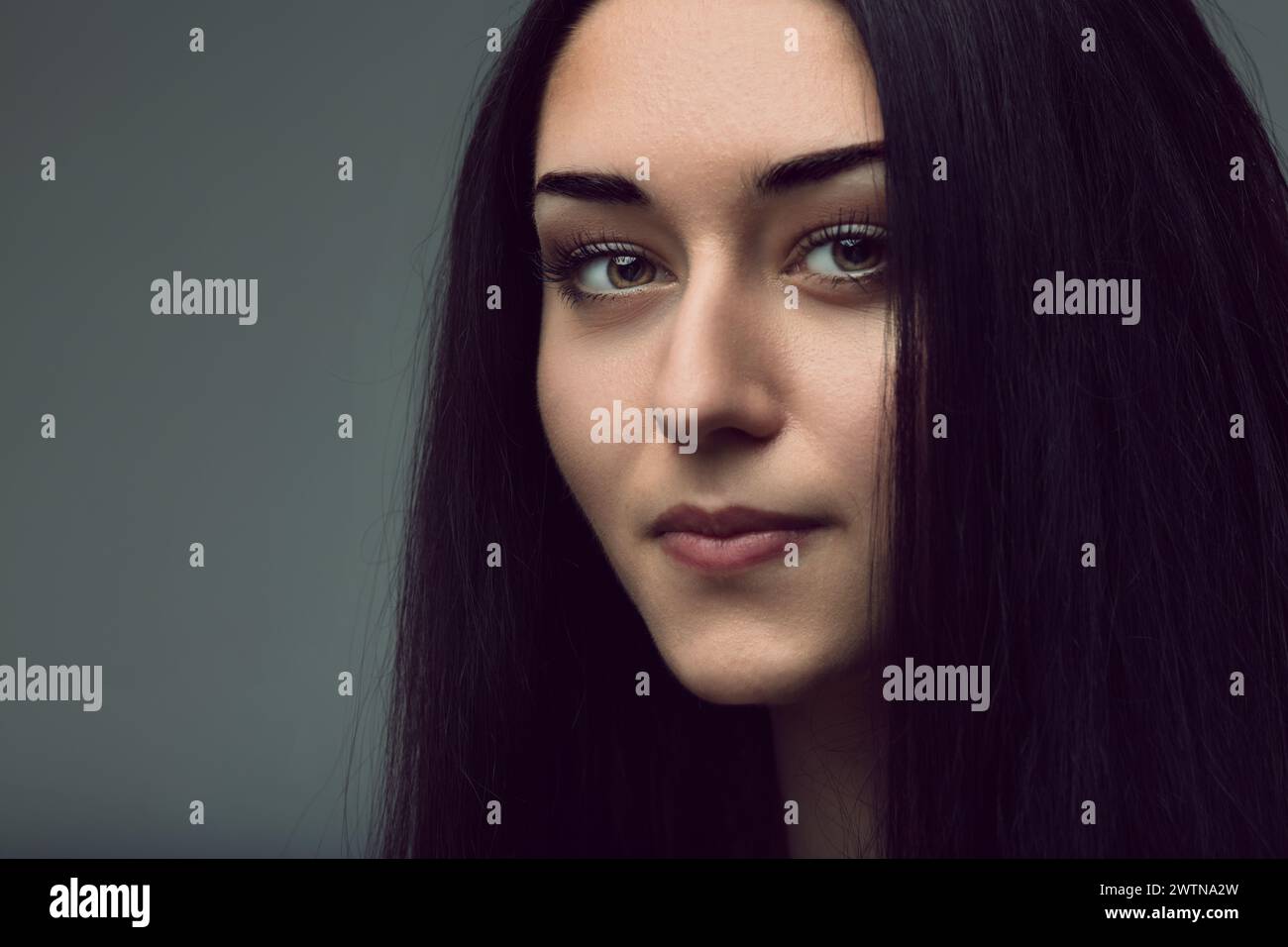 She looks on, her expression both inviting and inscrutable Stock Photo