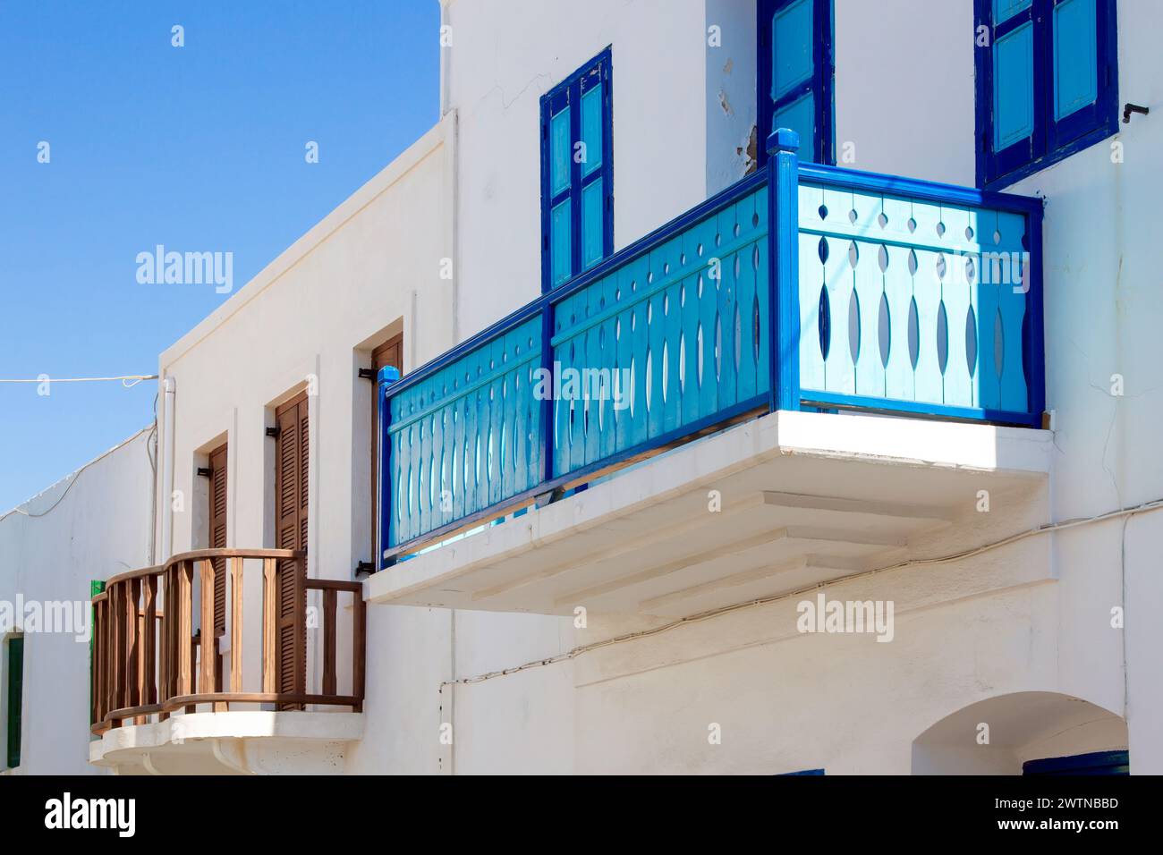 Traditional architecture of Greek islands, with wooden balconies painted in bright colors, alongside with the windows. Here as in Nisyros island. Stock Photo