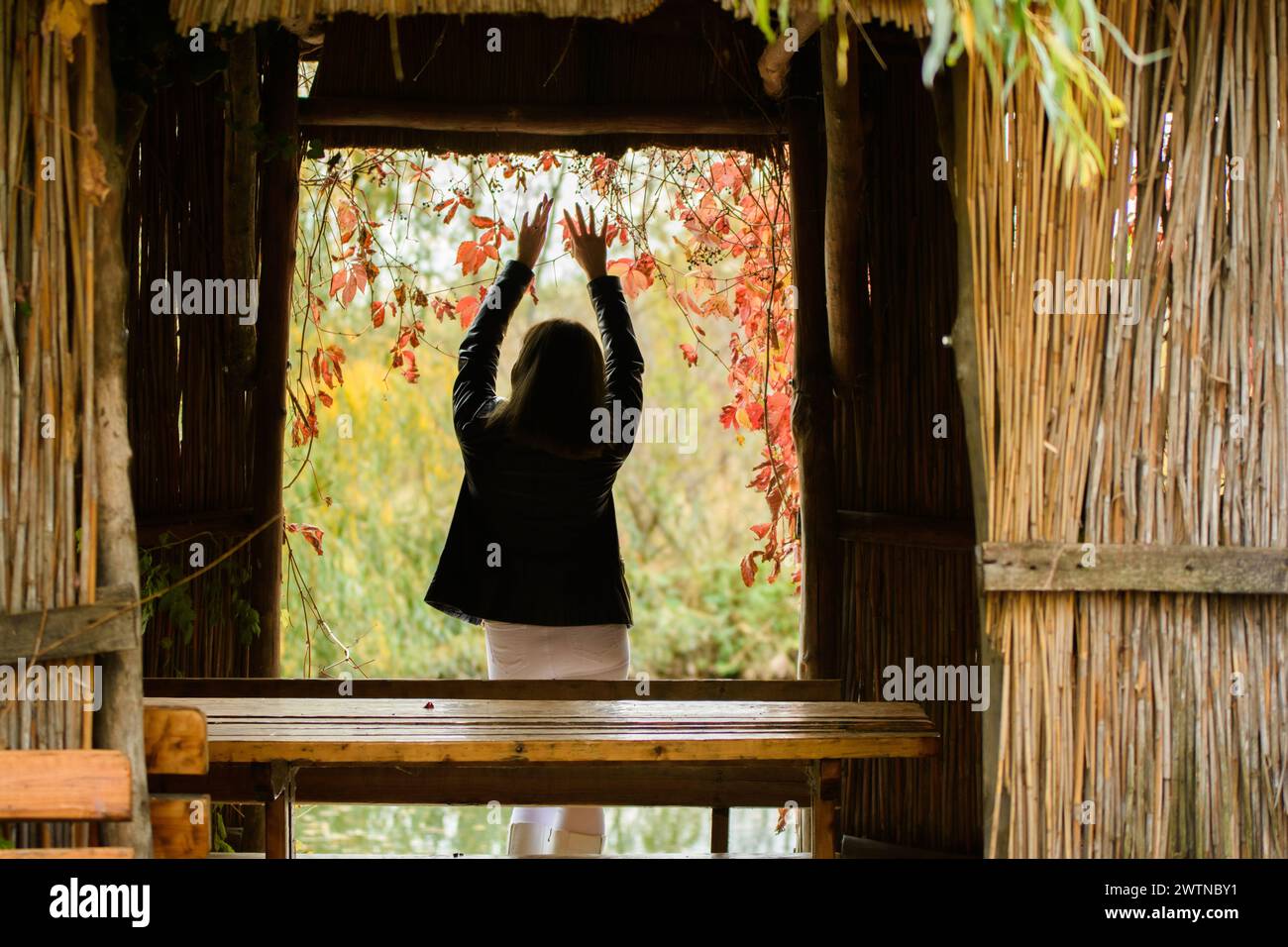 A young beautiful girl stands in the doorway of an old hut and raised ...