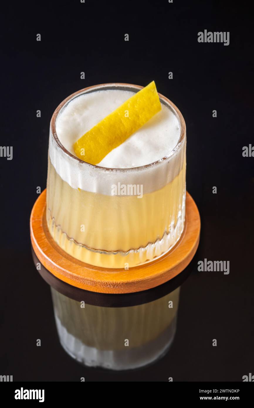 Glass of Whiskey sour cocktail garnished with lemon zest Stock Photo