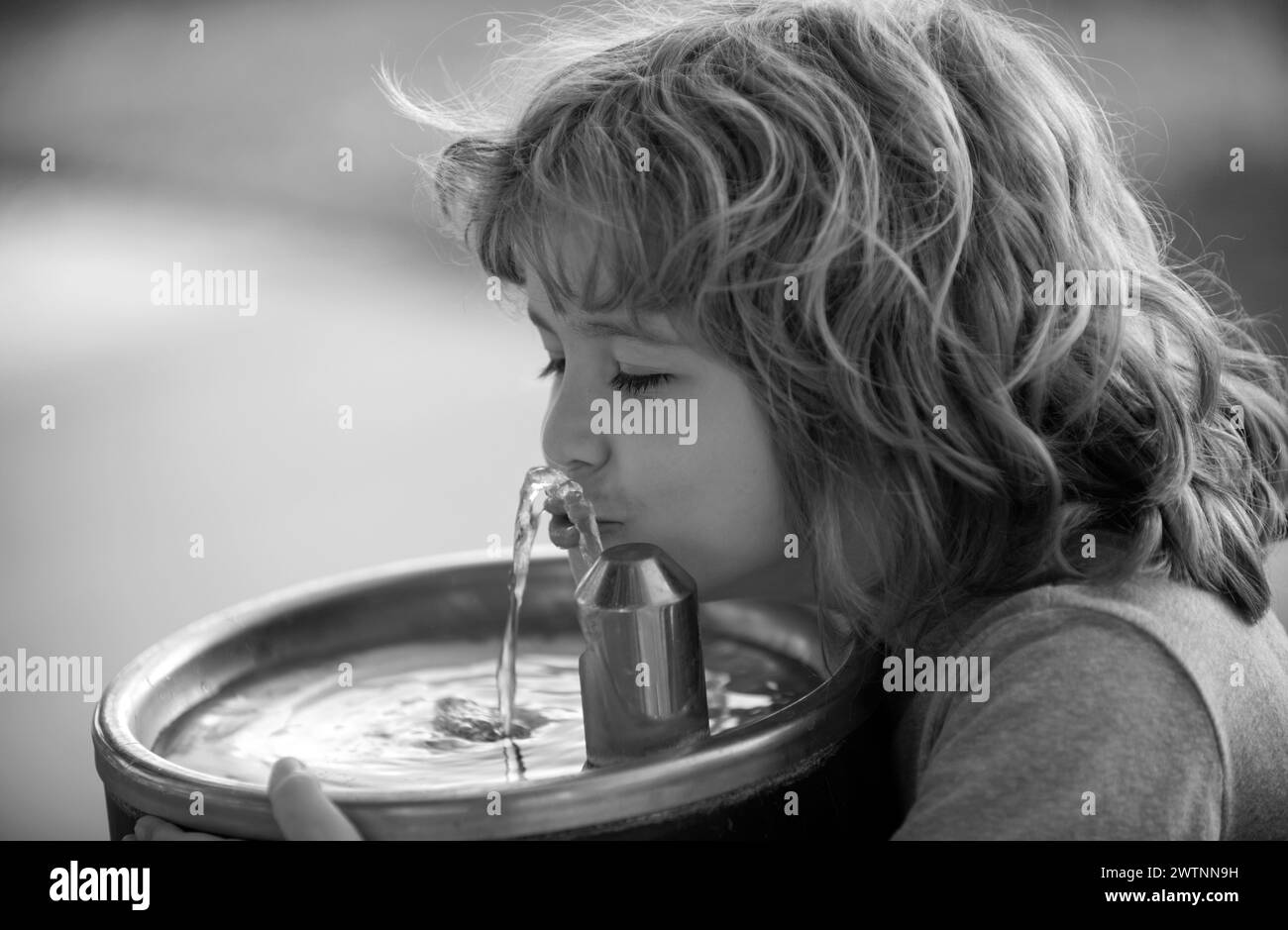 Child drinking water from outdoor water fountain outdoor. Stock Photo