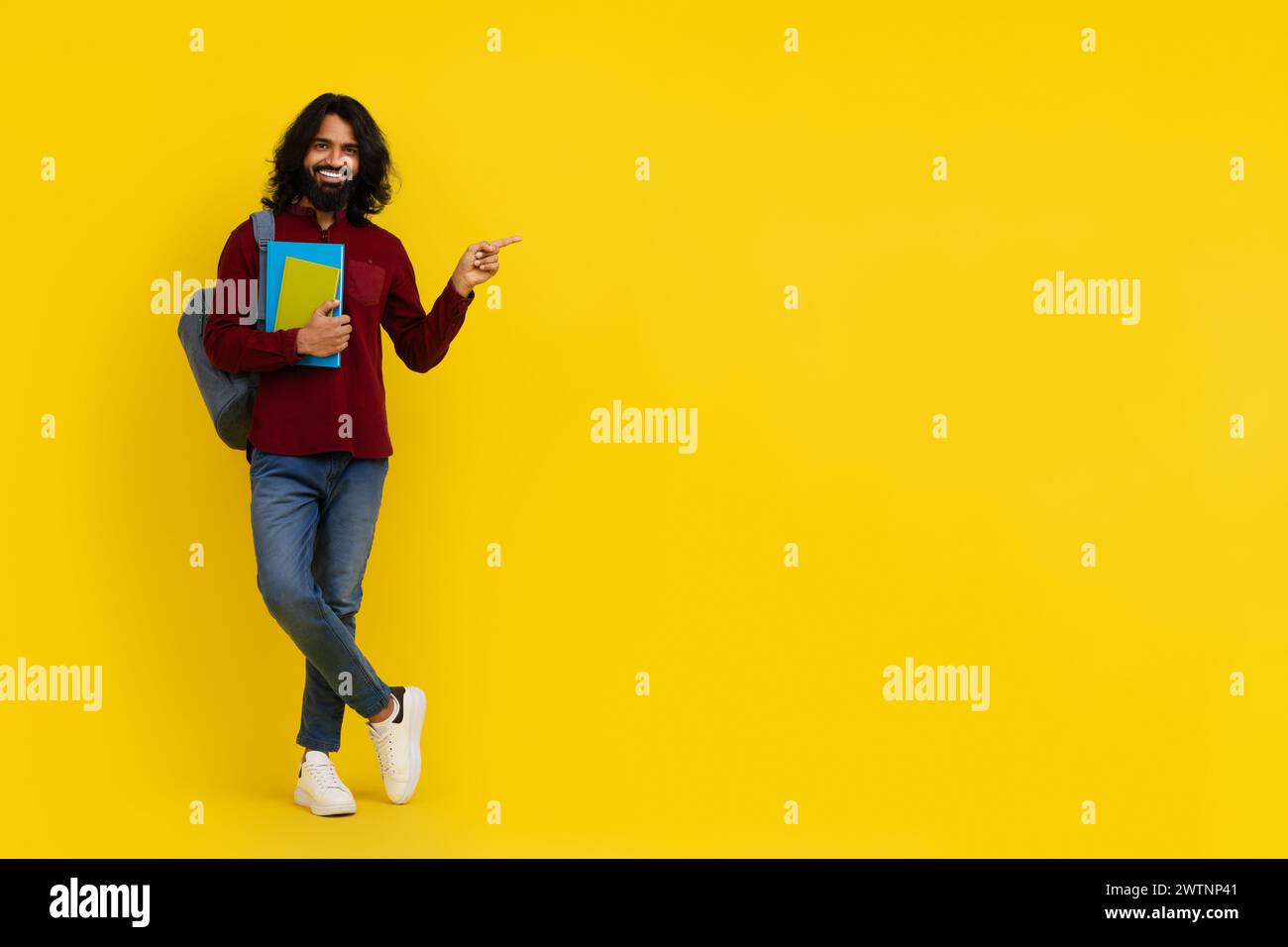 Cheerful young indian man student pointing at copy space Stock Photo