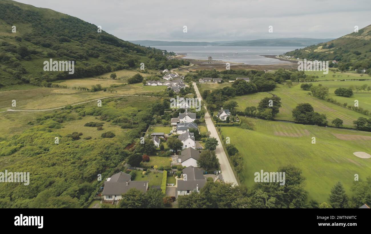 Scotland aerial view: whiskey distillery Loch Ranza, greenery village, mountain valley, camping town. Beautiful landscape on Lochranza Bay, Arran Island, United Kingdom. Footage shot Stock Photo