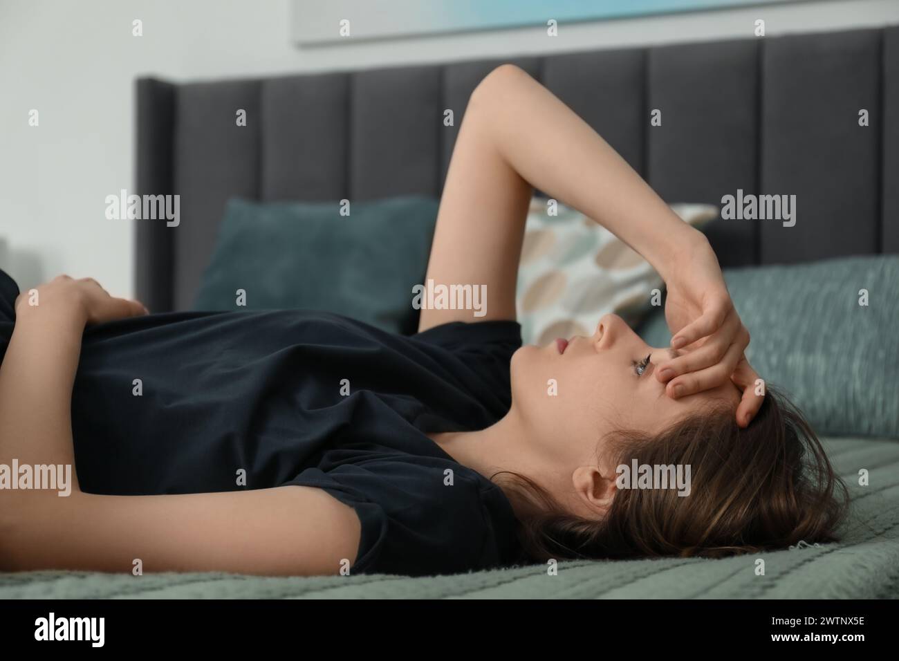 Sad young woman lying on bed at home Stock Photo - Alamy
