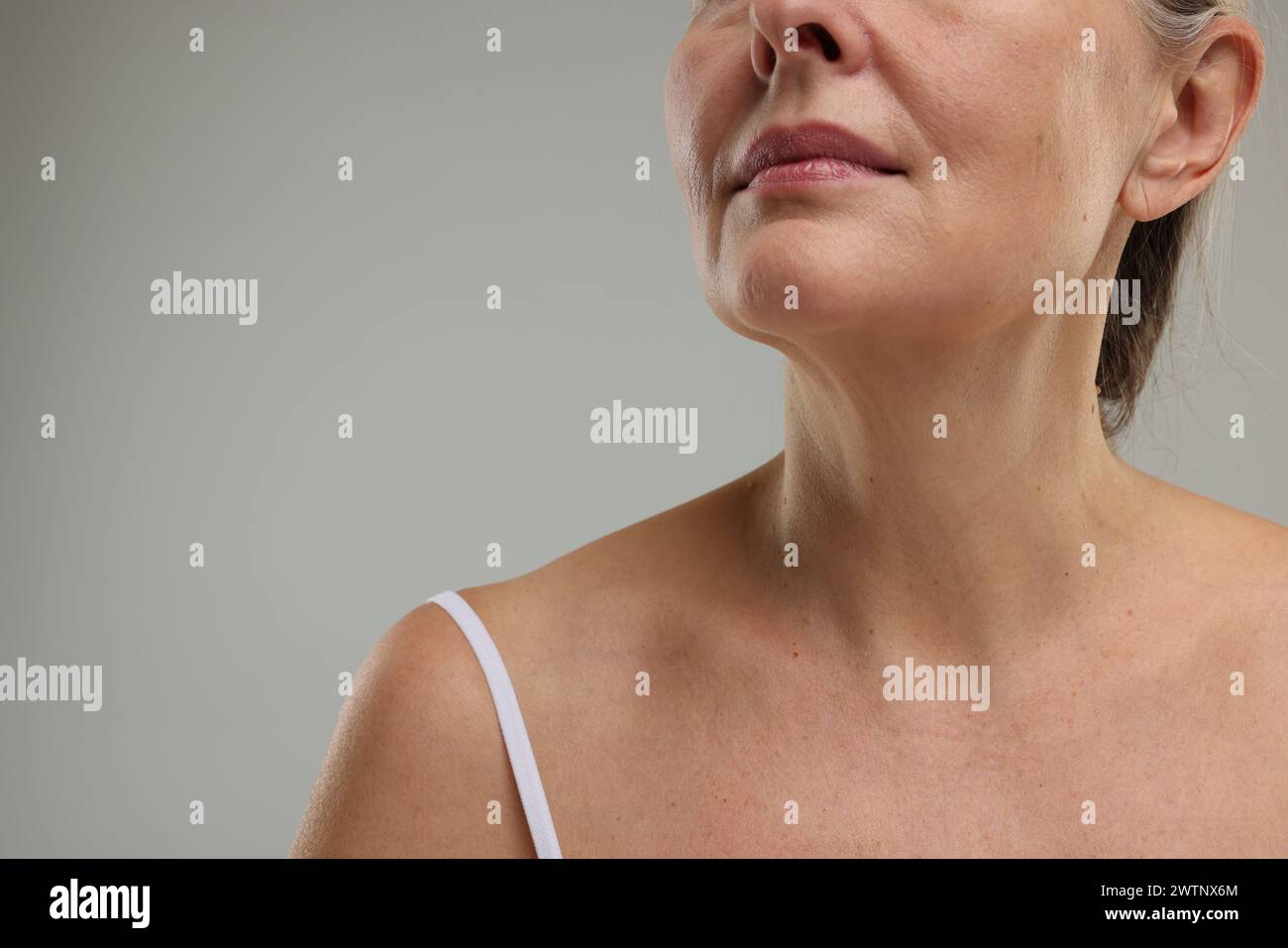 Mature woman with healthy skin on grey background, closeup. Space for text Stock Photo
